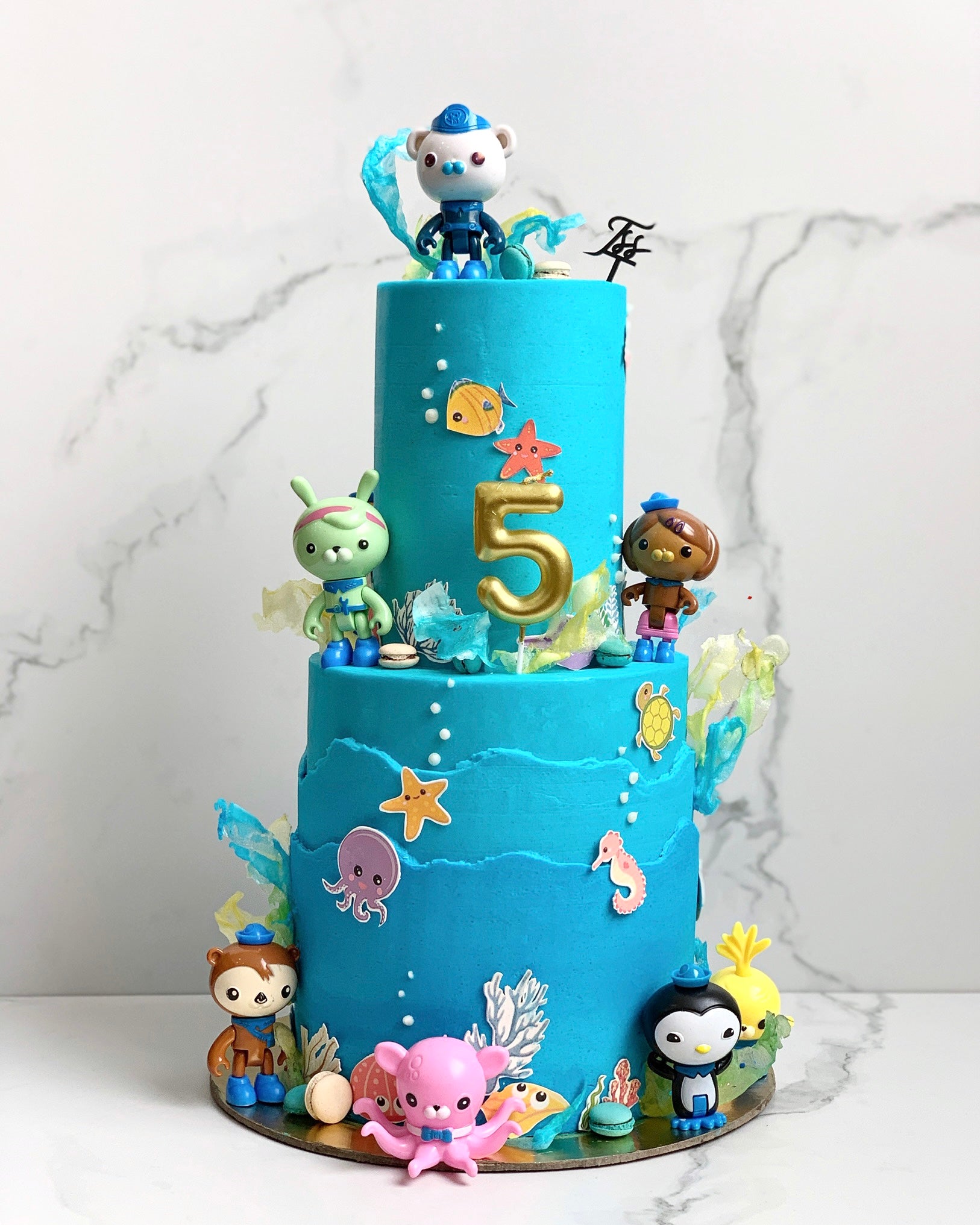 Colorful tiered kids cake from The Sinful Spoon with vibrant frosting and decorative sprinkles, perfect for celebrations.