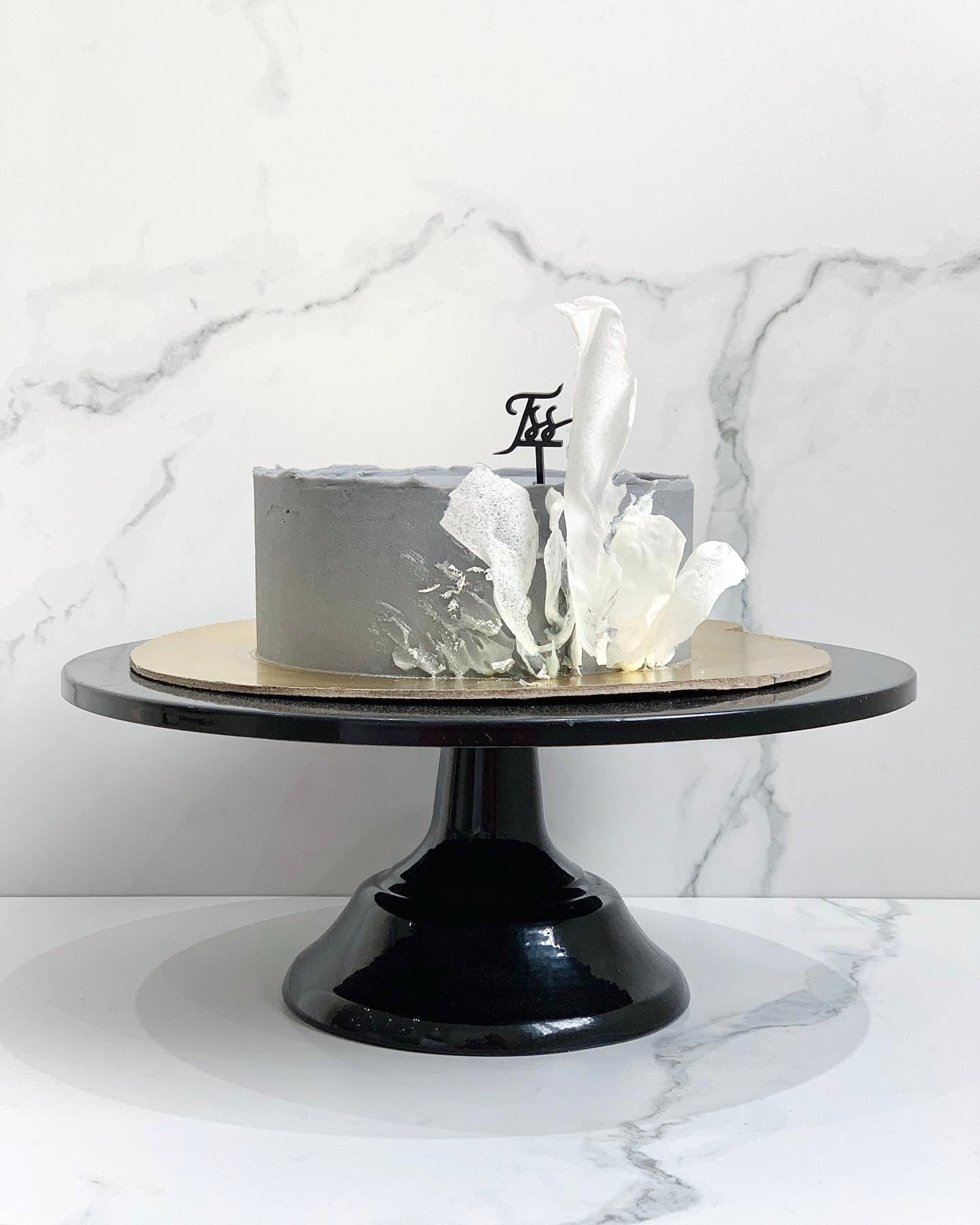 Slice of classic cake from The Sinful Spoon featuring layered sponge and creamy frosting on a white plate.