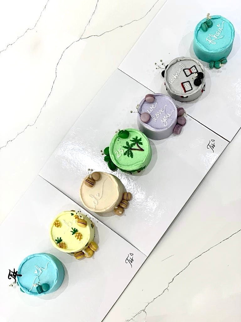 Colorful bento cakes from The Sinful Spoon with layered frosting and decorative toppings, perfect for celebrations.