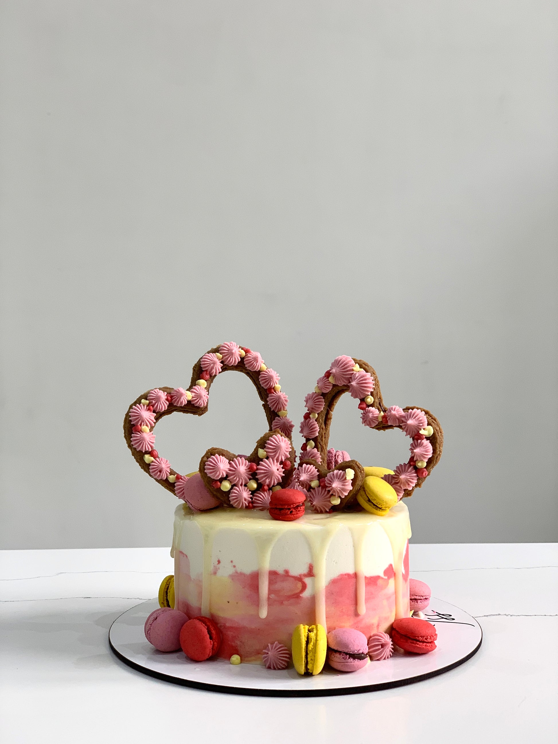 Valentine's Day cake from The Sinful Spoon featuring heart-shaped design with pink and red frosting and decorative sprinkles.