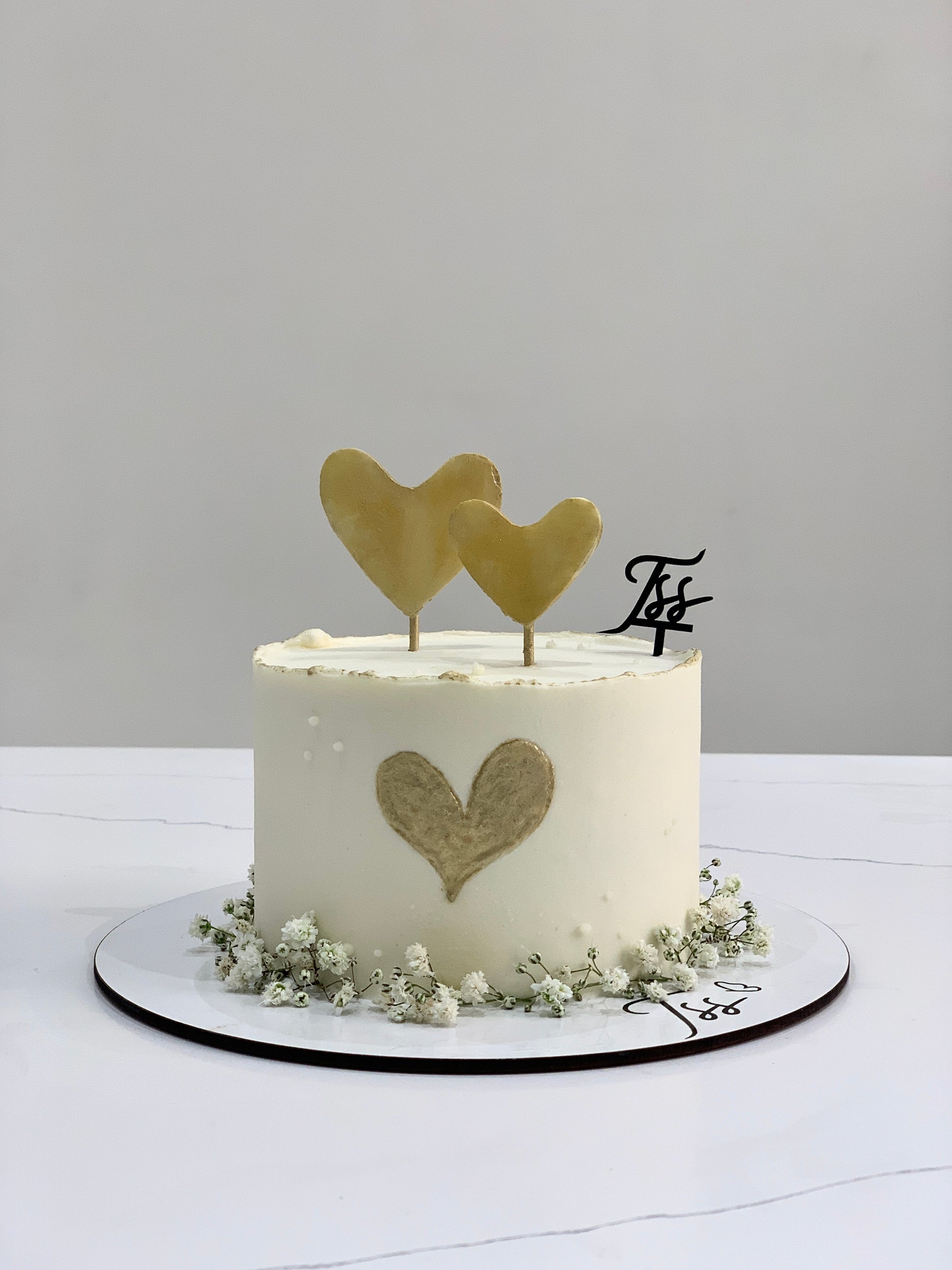 Valentine's Day cake from The Sinful Spoon decorated with pink frosting and heart-shaped accents on a white plate.