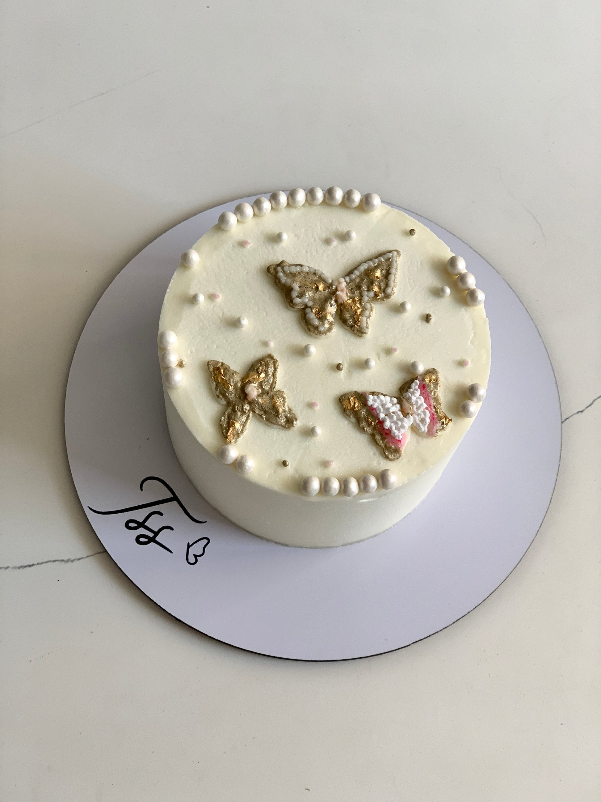 Decorative buttercream illustration cake by The Sinful Spoon with colorful floral and abstract designs on smooth icing.