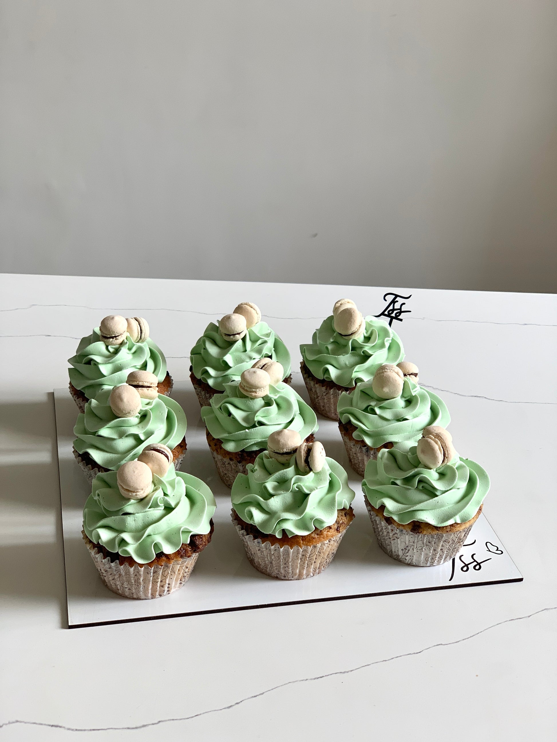 Colorful cupcakes with frosting and sprinkles on a plate, baked by The Sinful Spoon, showcasing vibrant dessert treats.
