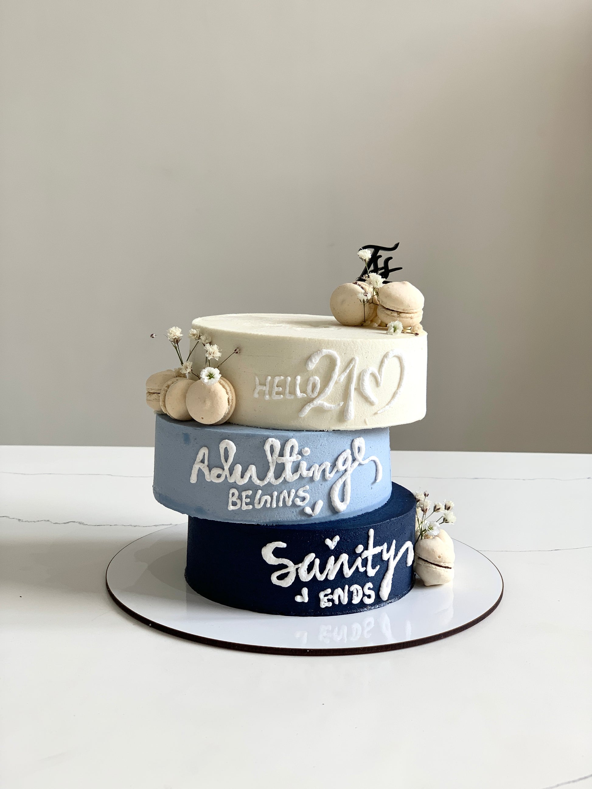 Asymmetrical cakes from The Sinful Spoon with layered frosting and decorative toppings on a white cake stand.