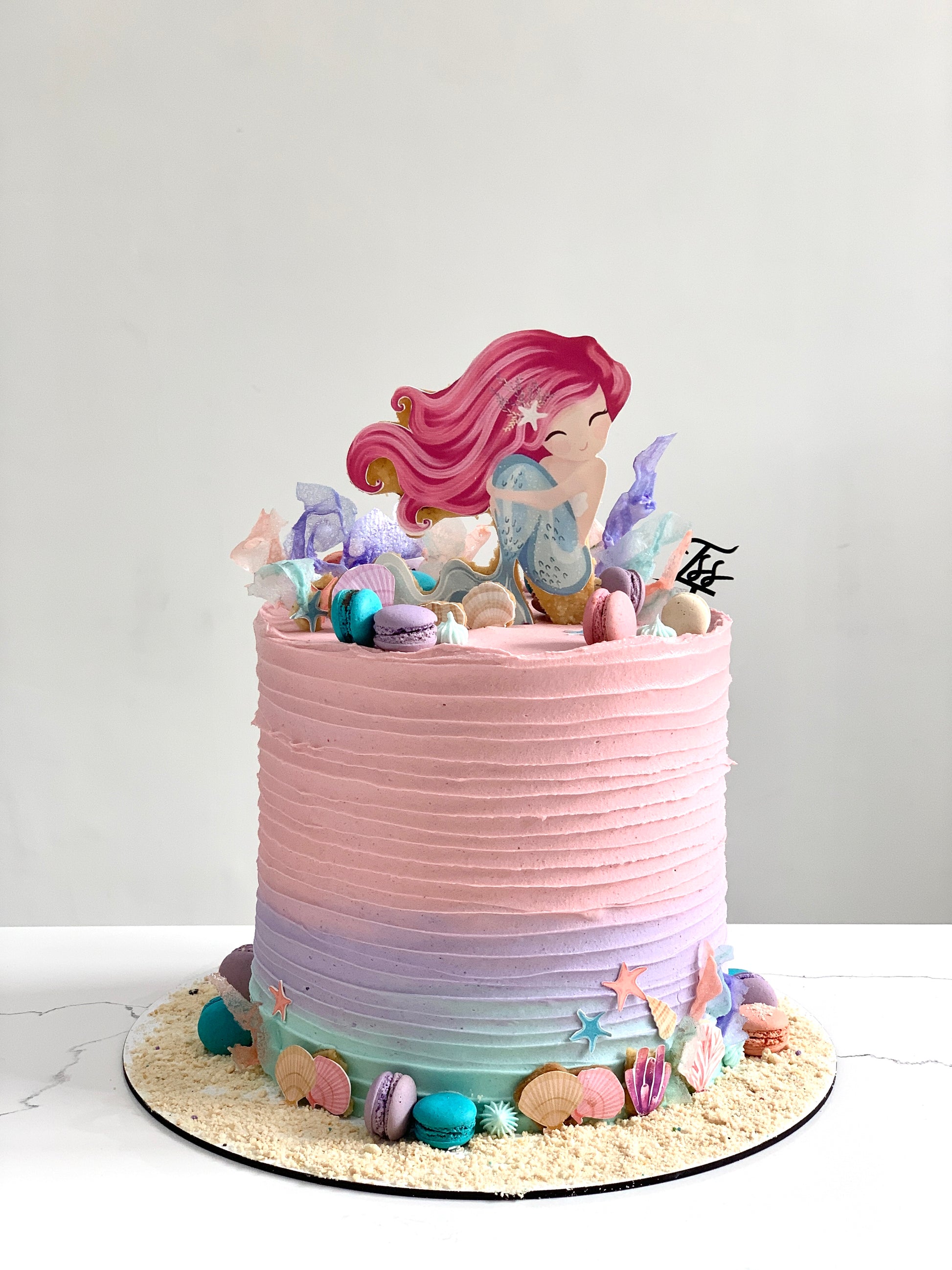 Edible paper cake featuring a baby girl design from The Sinful Spoon, decorated with colorful icing and edible details.
