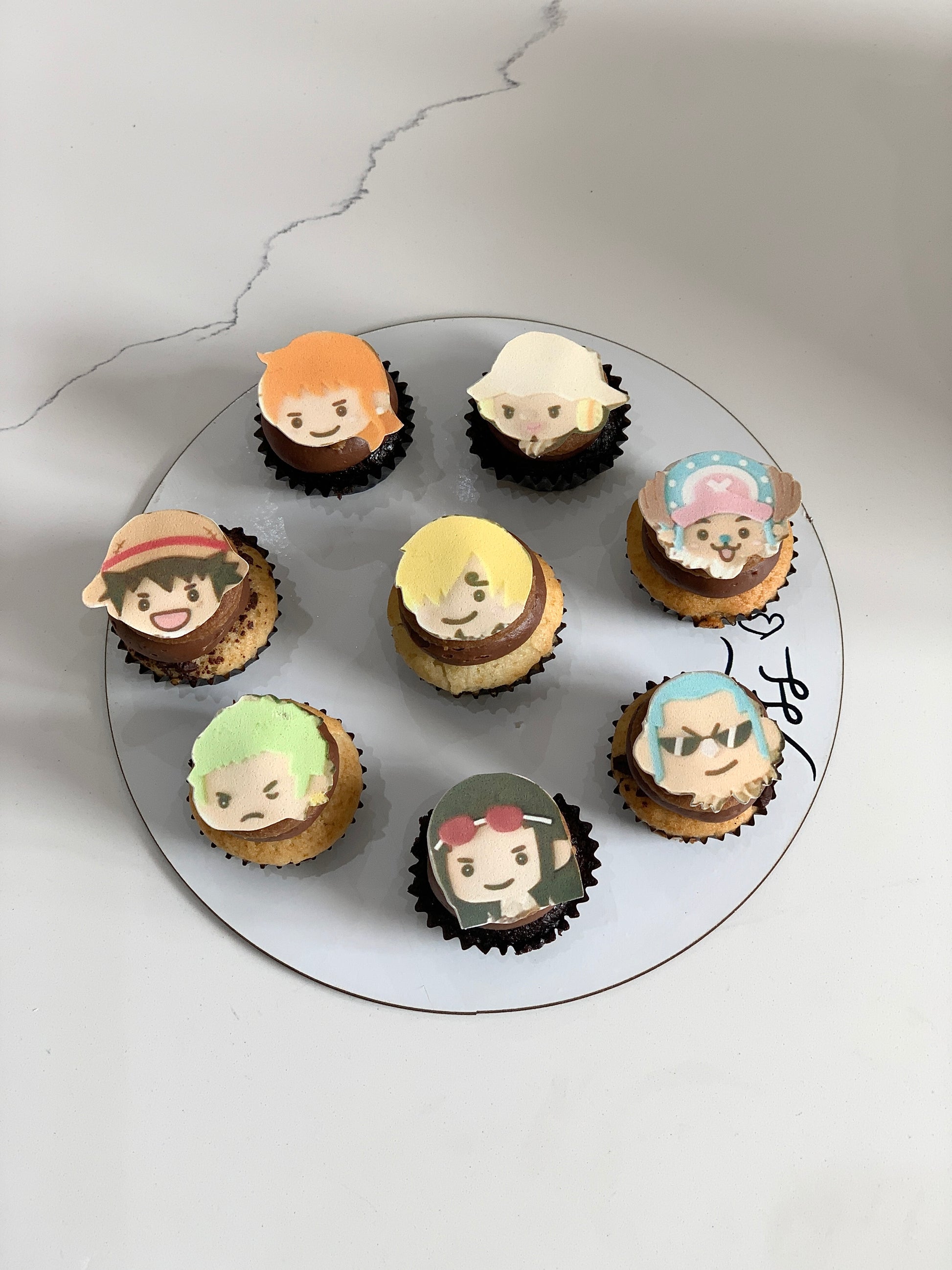 Colorful cupcakes from The Sinful Spoon with swirled frosting and decorative sprinkles on a white plate.