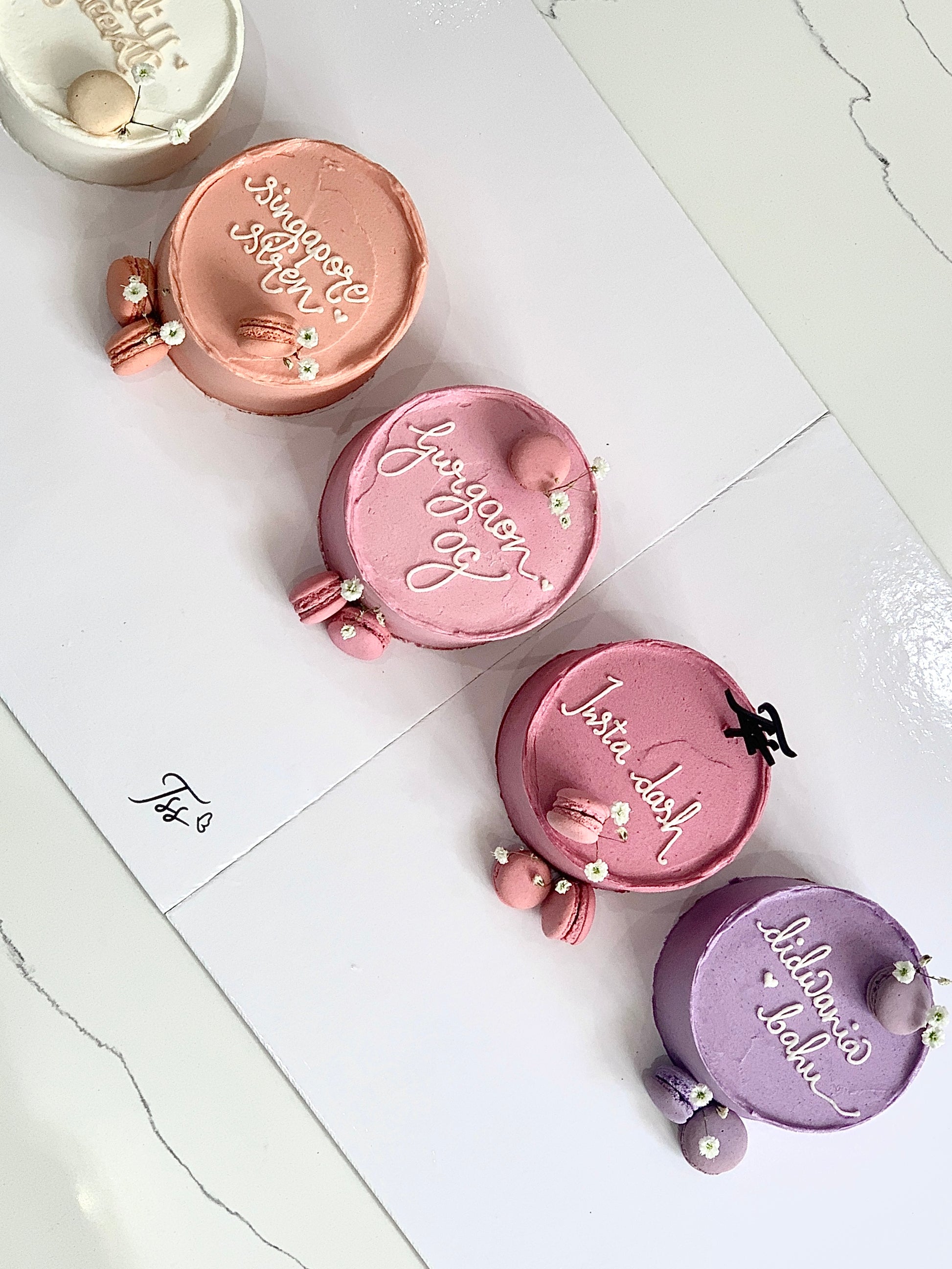 Mini Bento Cakes by The Sinful Spoon, assorted colorful layered desserts with decorative toppings on a white plate.
