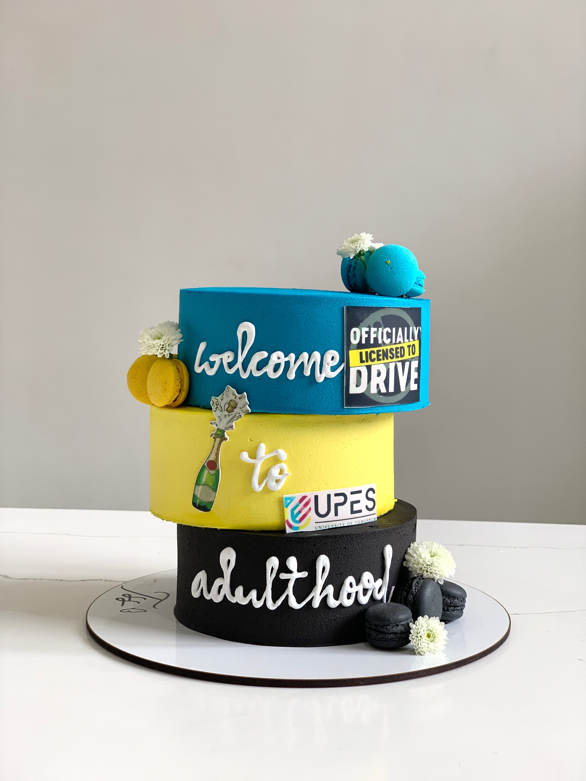 Asymmetrical cake from The Sinful Spoon with layered frosting and decorative toppings on a white plate.