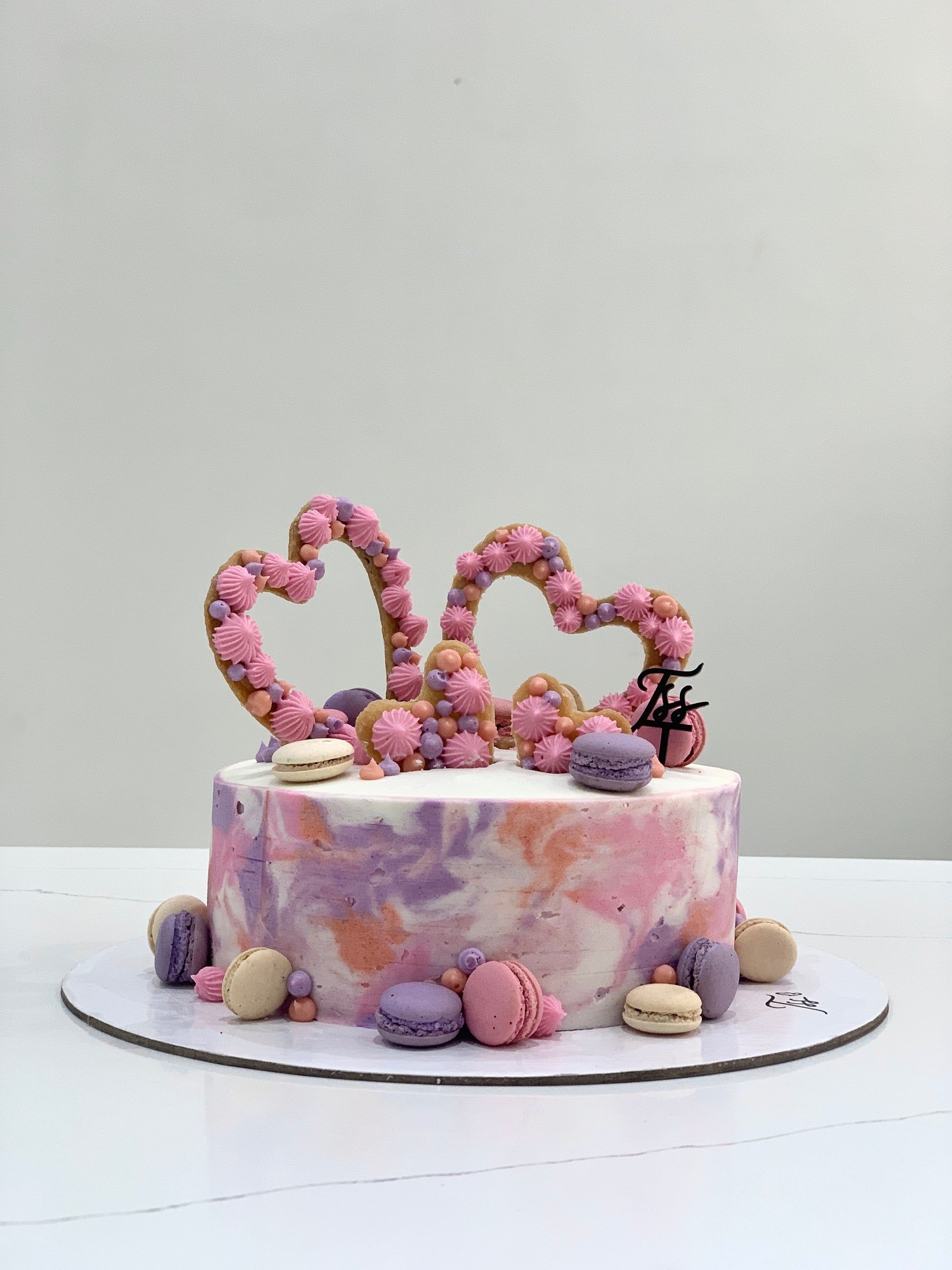 Valentine's Day cake from The Sinful Spoon with pink frosting and heart-shaped decorations on top.
