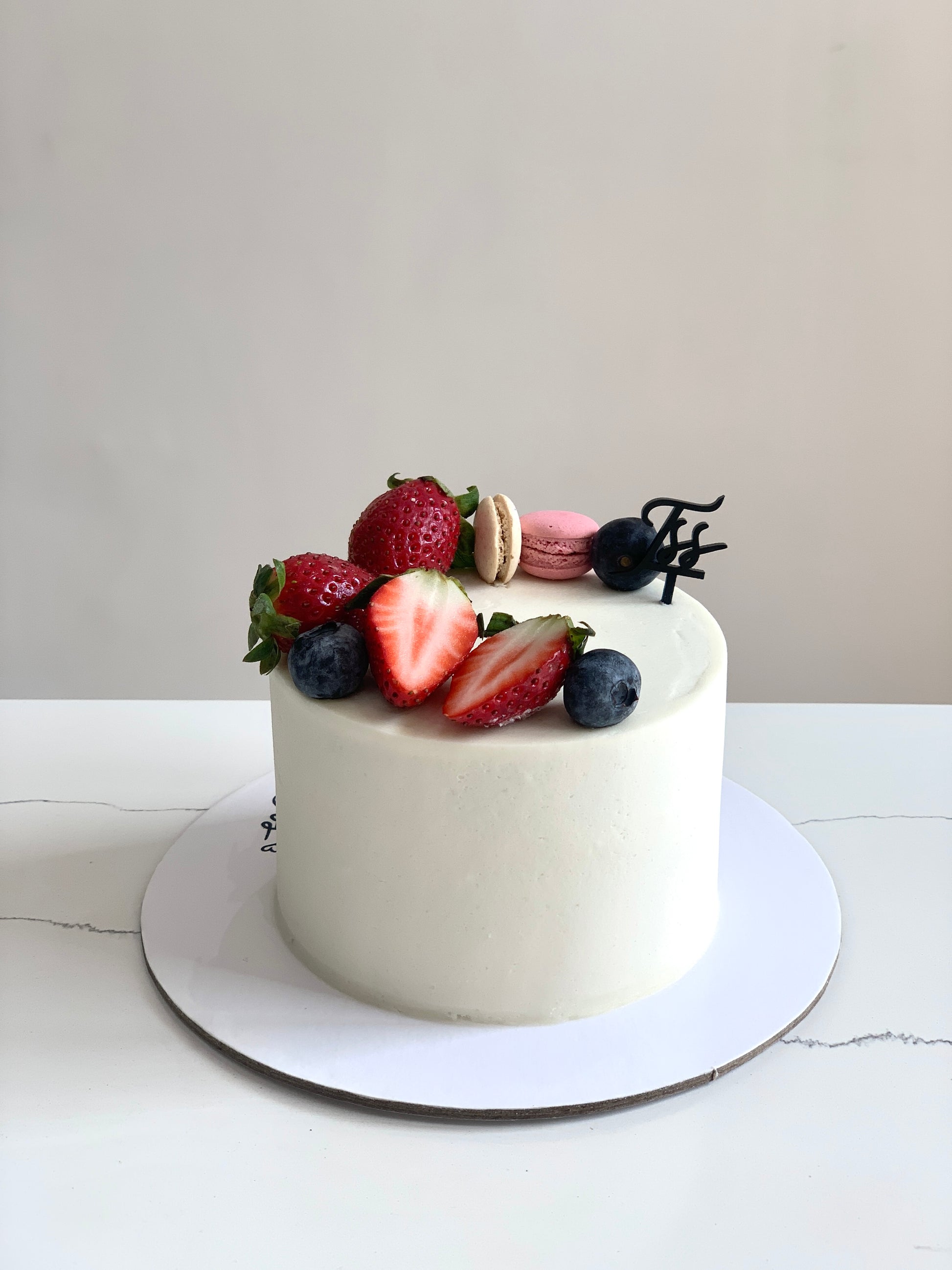 Fresh fruit cake from The Sinful Spoon featuring colorful sliced fruit and moist cake layers on a white plate.