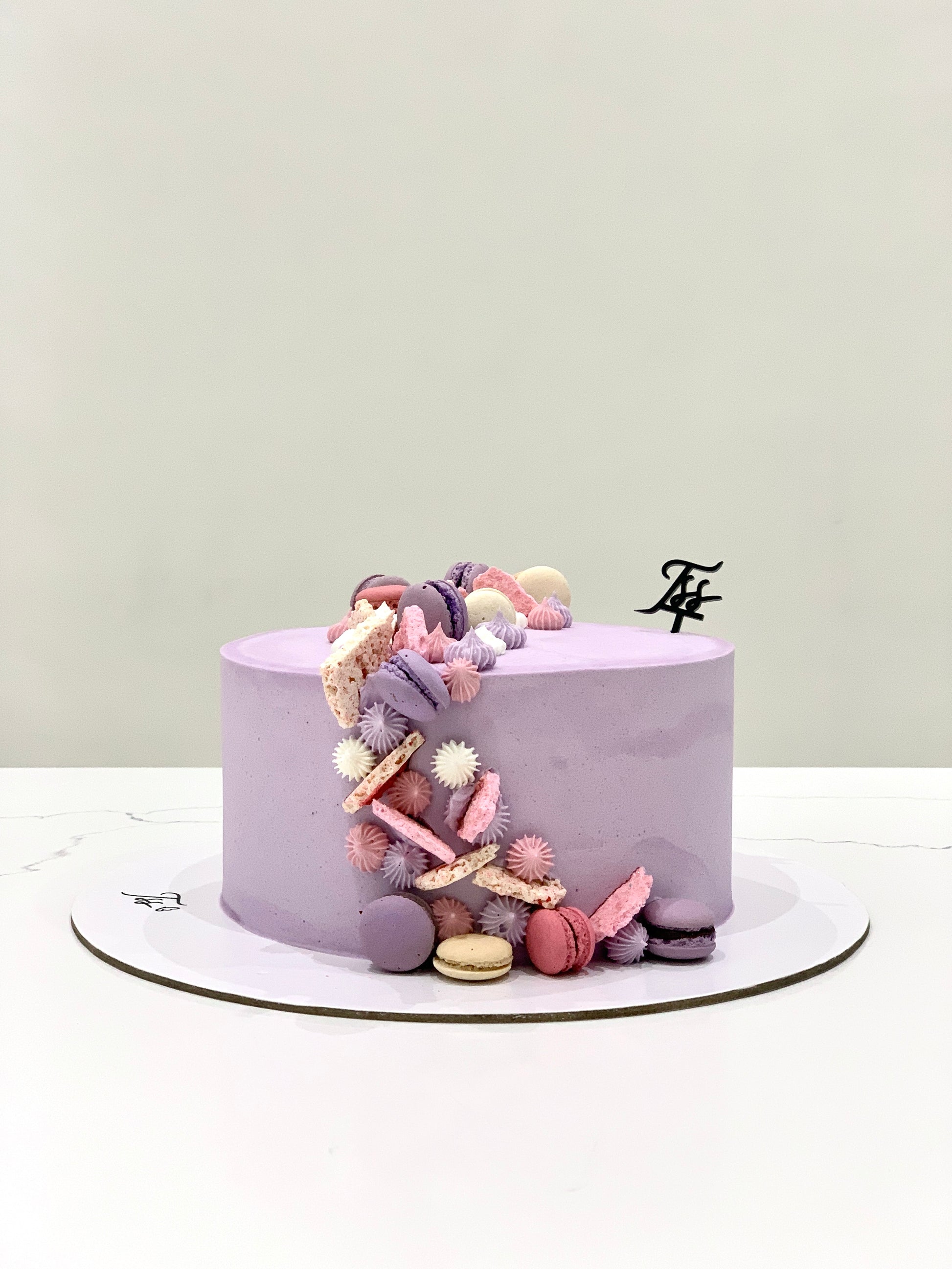 A slice of Classic Cake from The Sinful Spoon with creamy frosting and colorful sprinkles on a white plate.