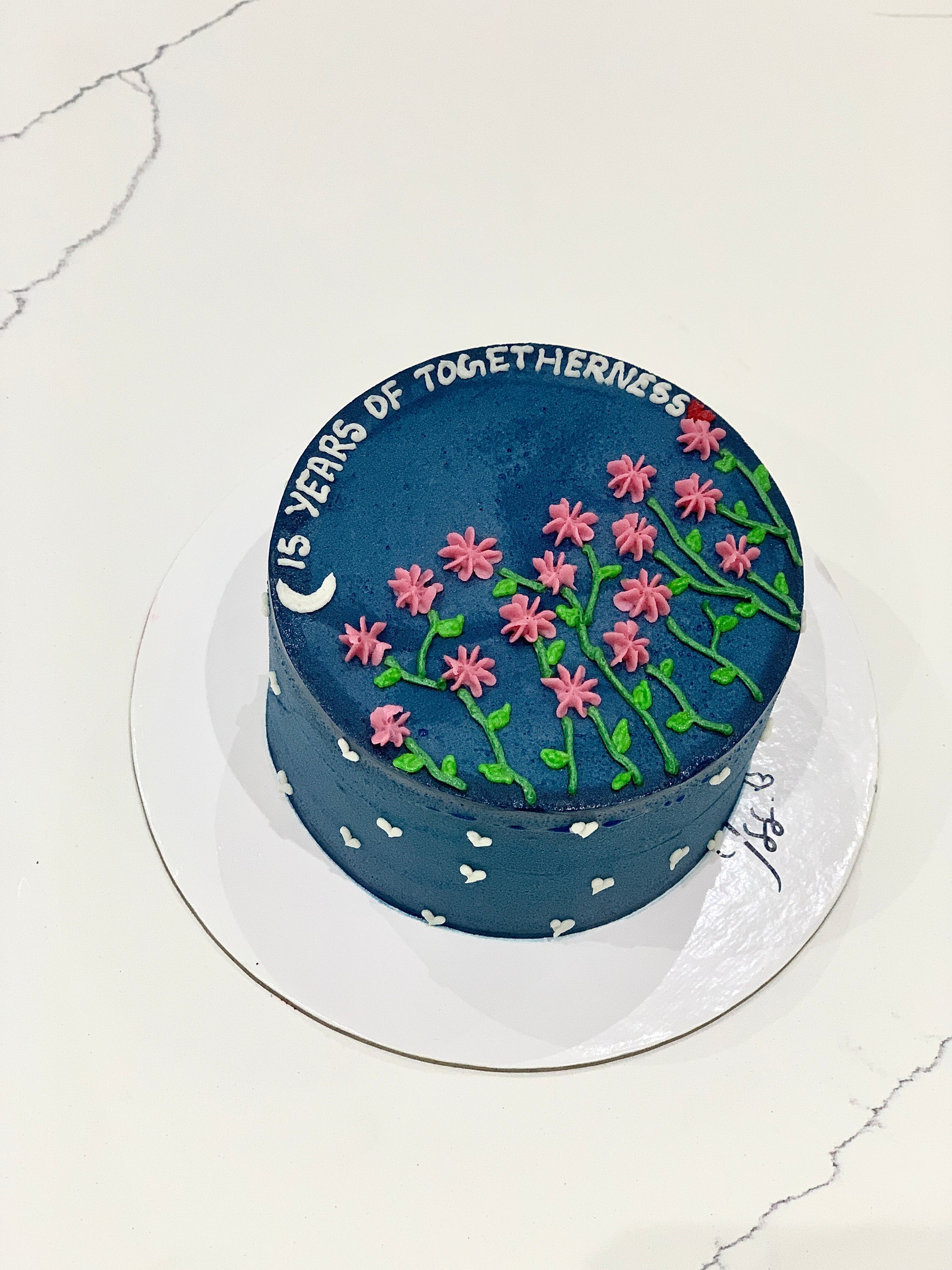 Decorative buttercream flower cake by The Sinful Spoon with intricate floral designs and pastel colors on a white cake.