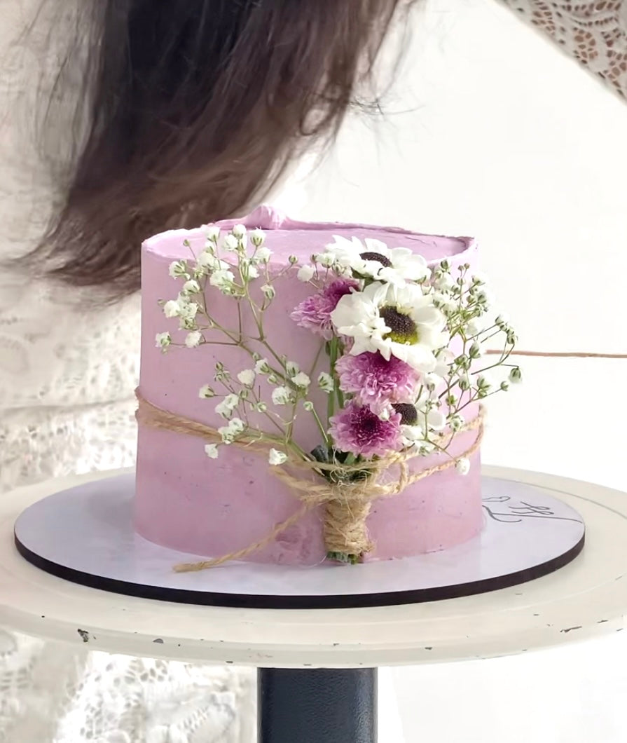 Decorative Mother's Day cake from The Sinful Spoon with floral icing and colorful decorations on a white plate.