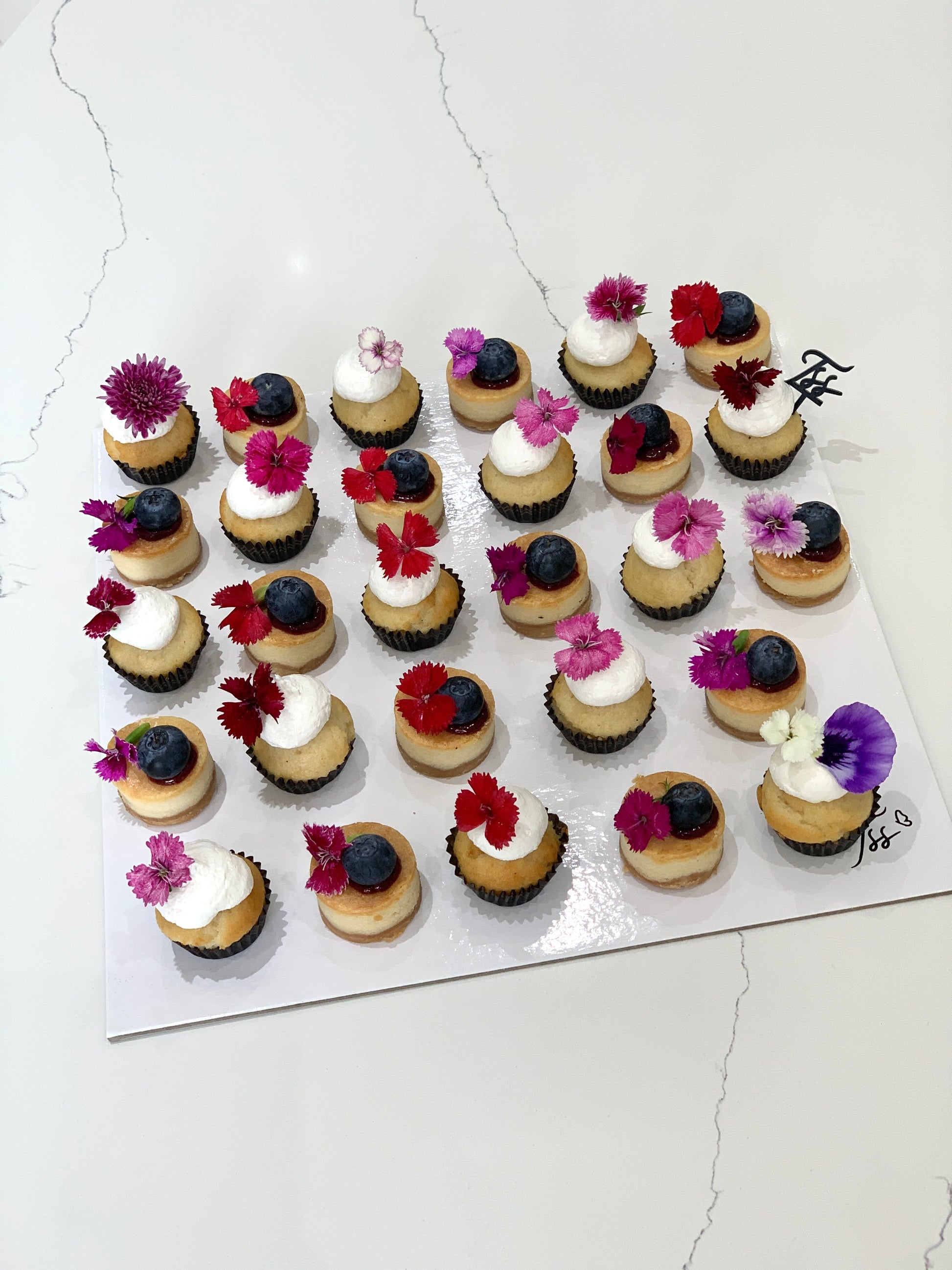Colorful cupcakes from The Sinful Spoon with swirled frosting and sprinkles, arranged on a decorative plate.