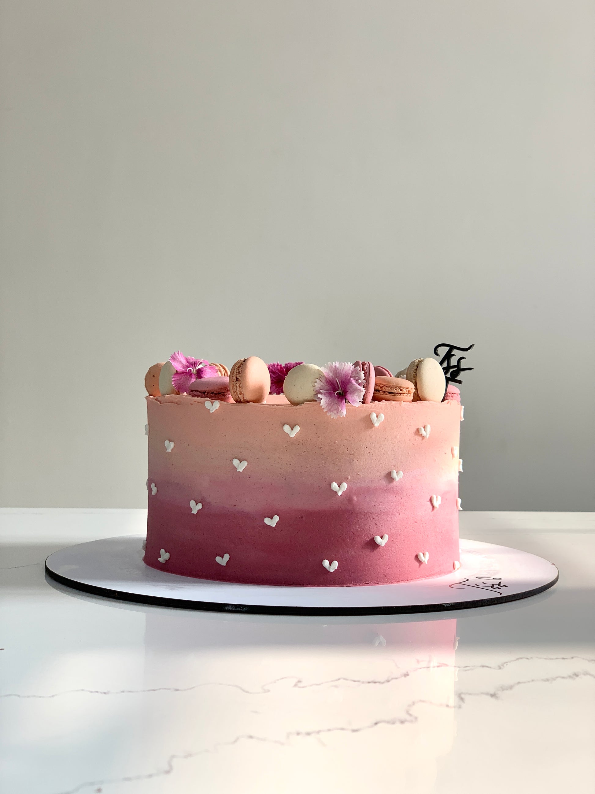 Slice of classic cake from The Sinful Spoon showcasing layered sponge and creamy frosting on a white plate.