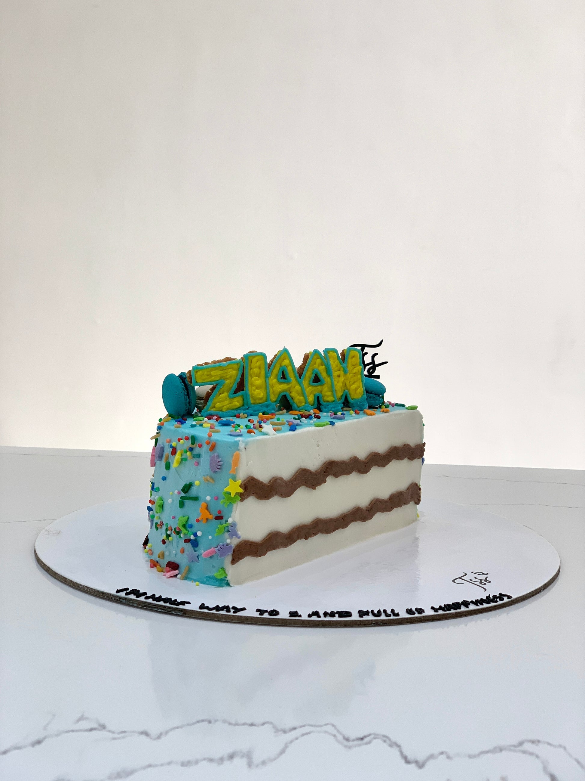 Half birthday cake from The Sinful Spoon featuring colorful frosting and festive decorations on a decorated table.
