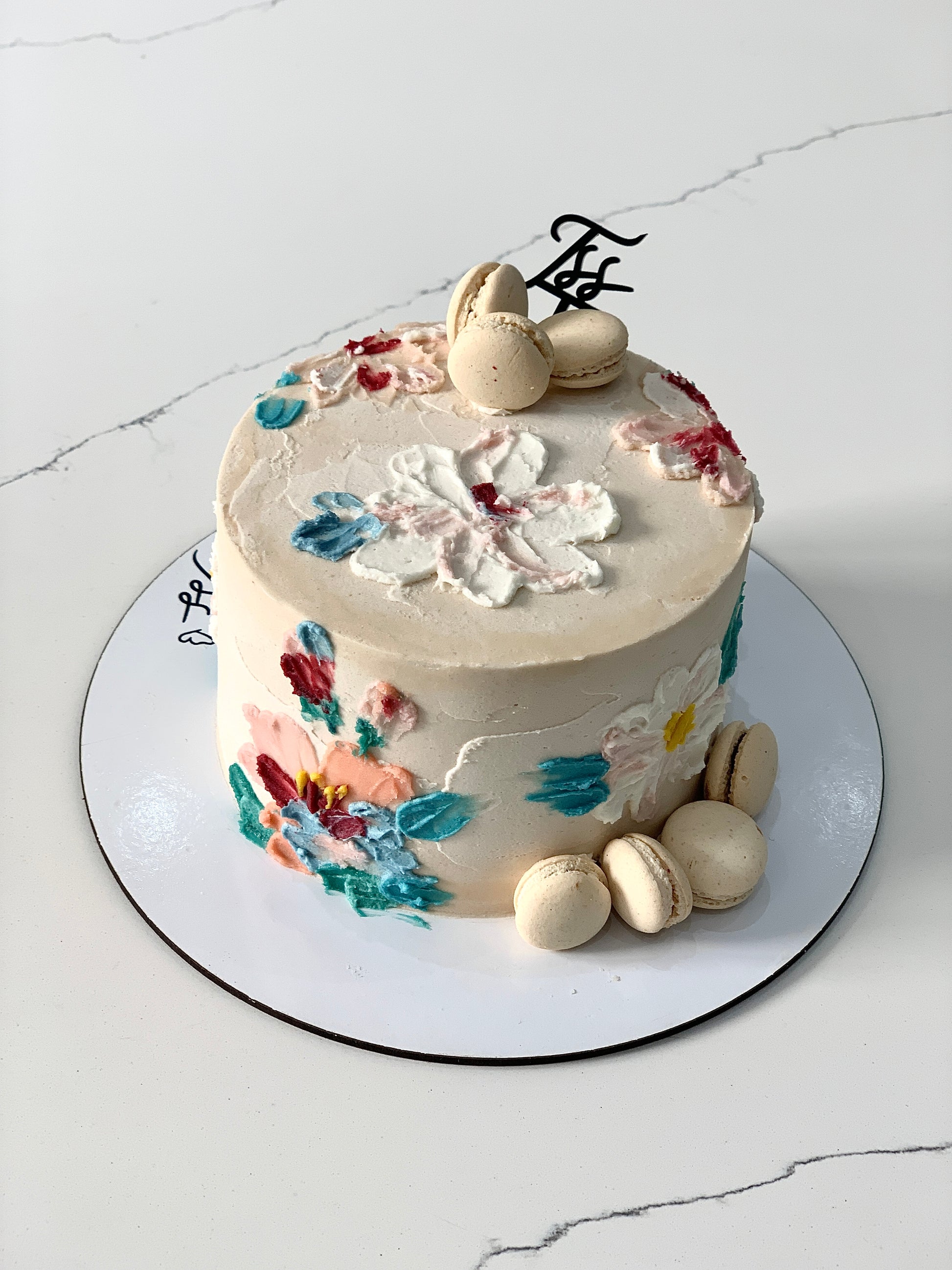 Decorative buttercream flower cakes by The Sinful Spoon featuring colorful floral designs on layered cake surfaces.