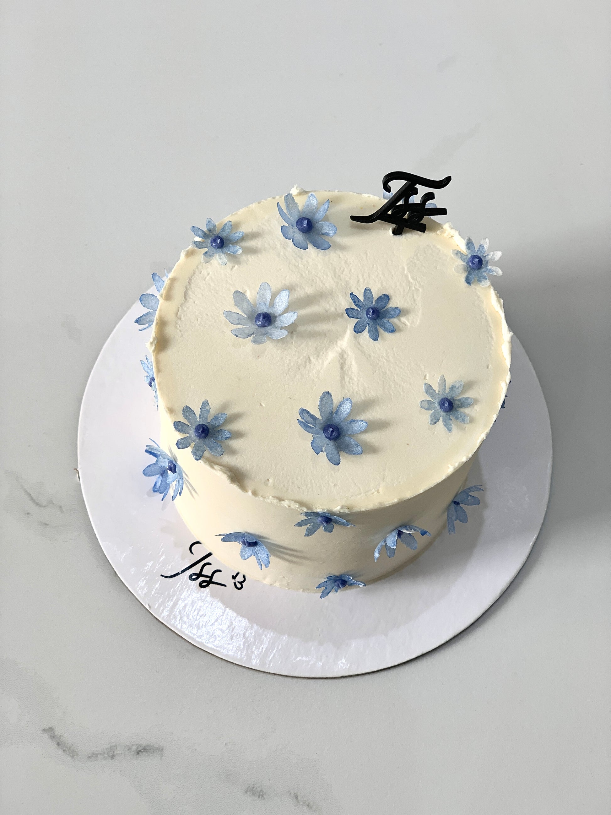 Decorative buttercream flower cakes by The Sinful Spoon with colorful floral designs on a white background.