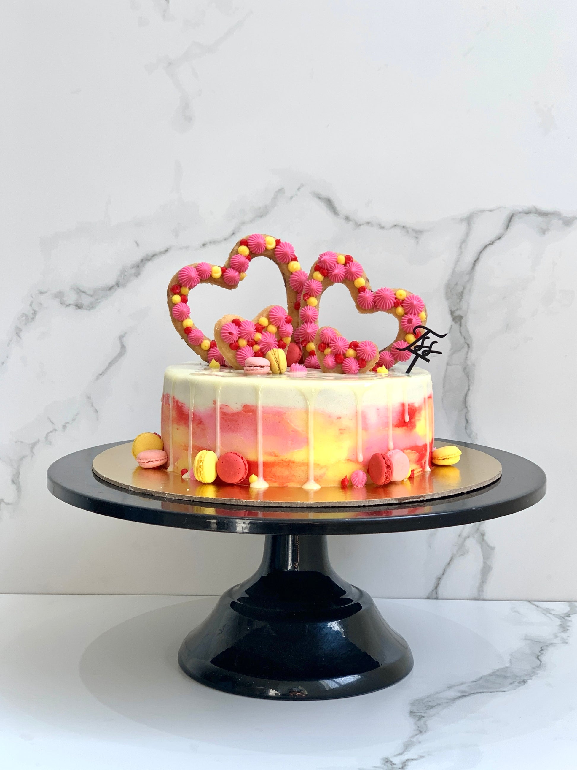 Valentine's Day cake from The Sinful Spoon with pink frosting, heart-shaped decorations, perfect for romantic celebrations.
