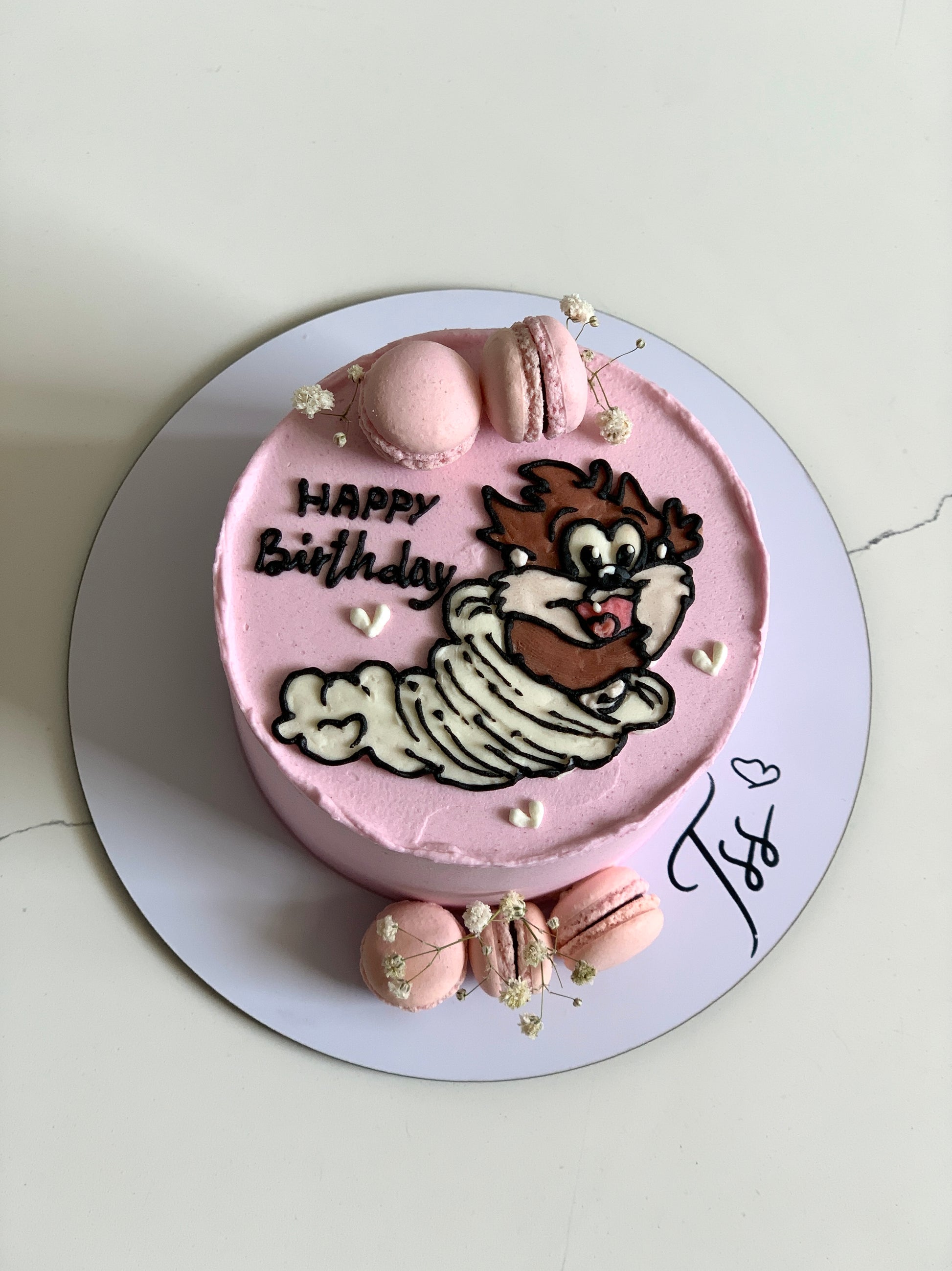 Decorative buttercream illustration cake with colorful floral designs from The Sinful Spoon, displayed on a white cake stand.