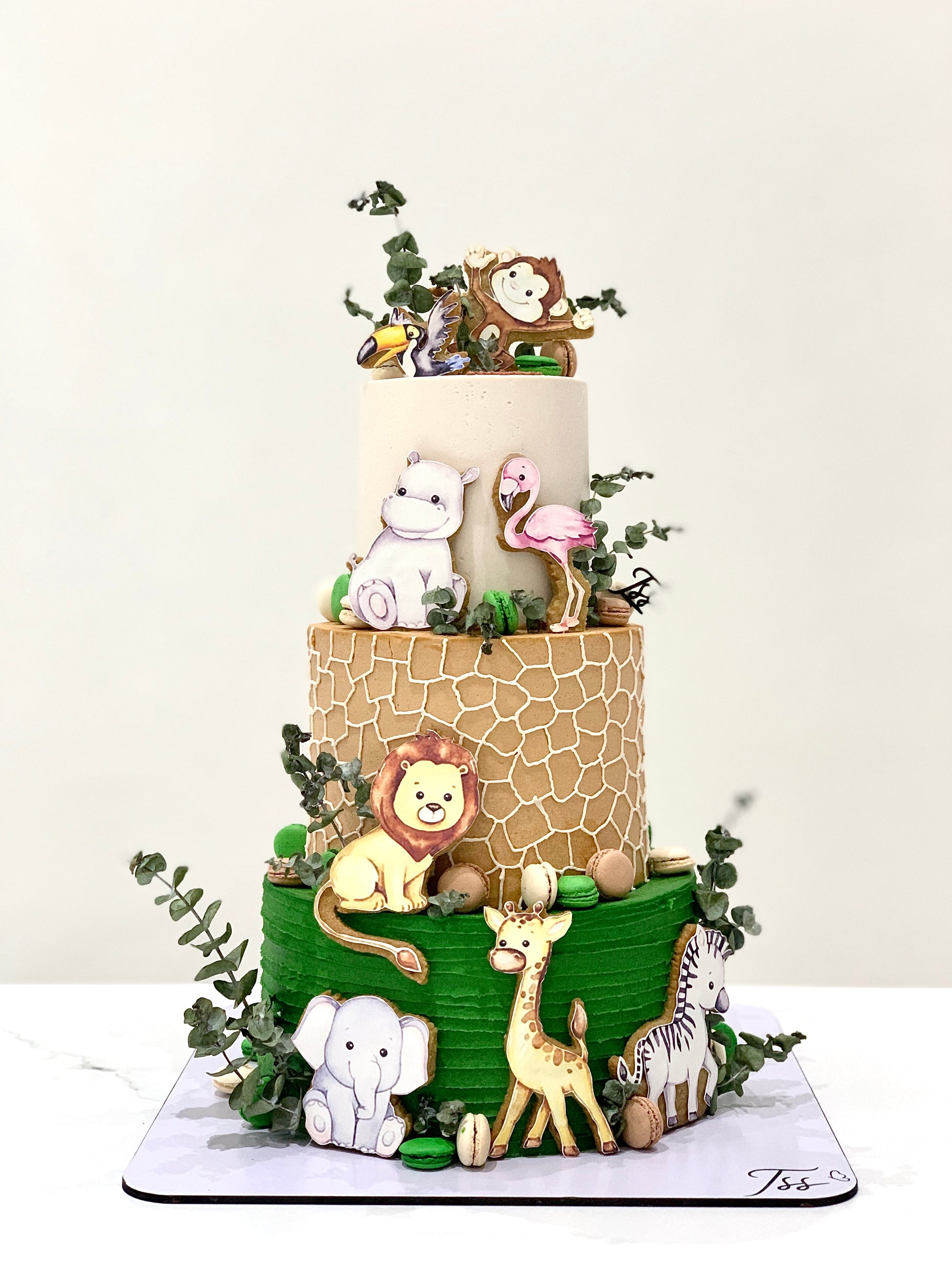 Colorful tiered kids cake by The Sinful Spoon with playful frosting and decorations on a white background.