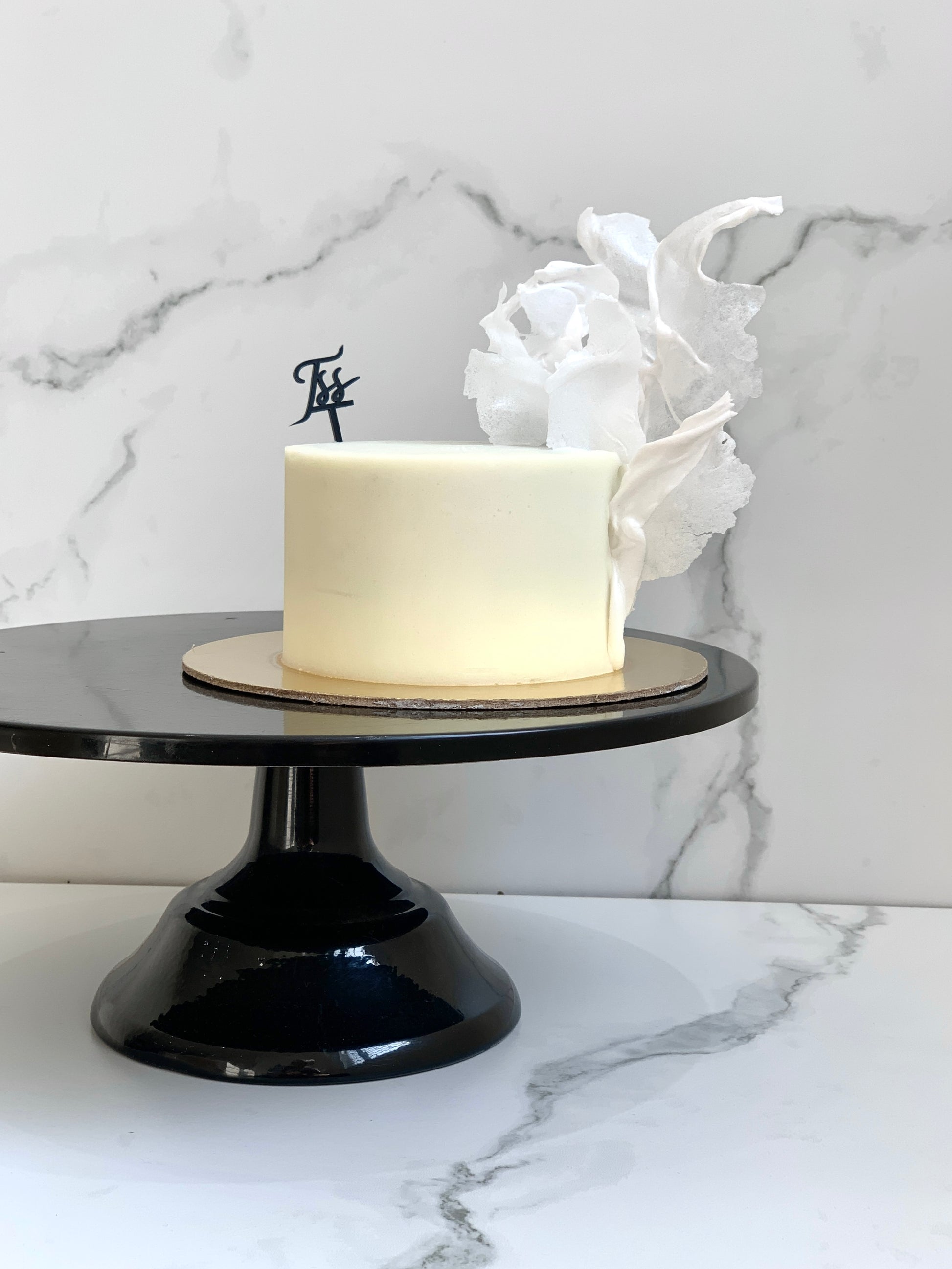 A classic cake from The Sinful Spoon featuring layered frosting and decorative toppings on a white plate.
