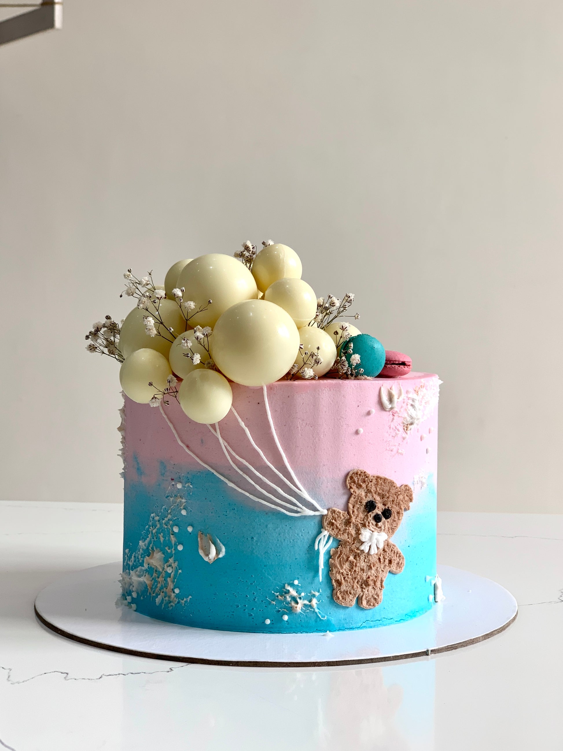 Decorative baby shower cake from The Sinful Spoon with pastel frosting and adorable baby-themed toppers, perfect for celebration.