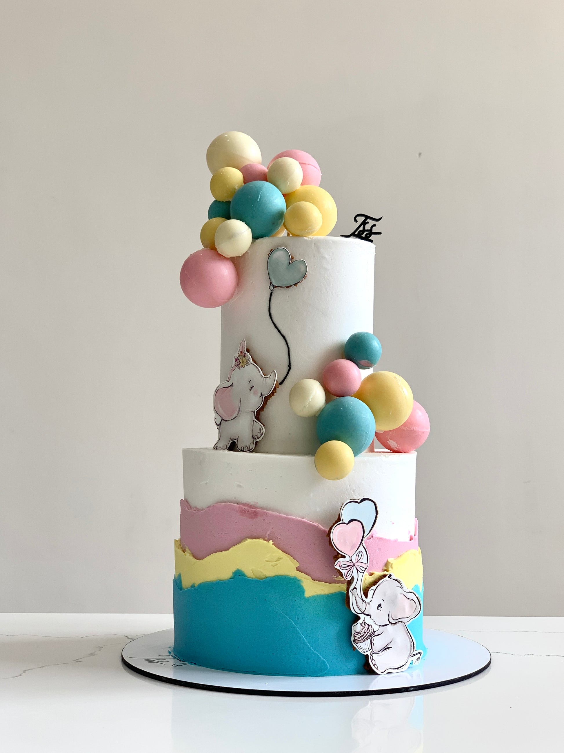 Decorative baby shower cake from The Sinful Spoon with pastel frosting and cute baby-themed decorations.