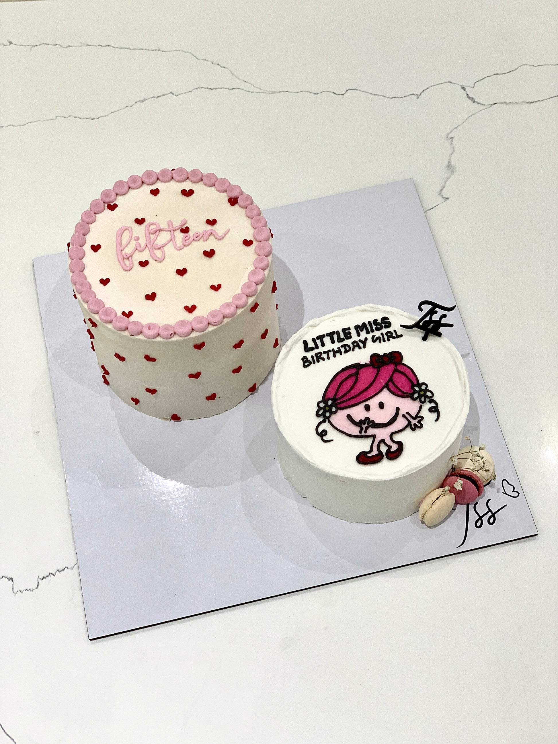 Colorful bento cakes from The Sinful Spoon featuring layered frosting and decorative toppings on a white plate.