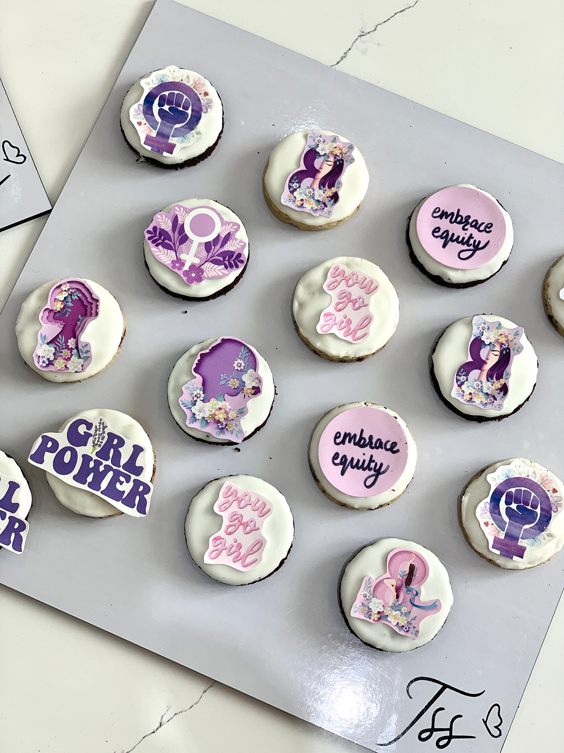 Assorted colorful cupcakes with frosting and sprinkles from The Sinful Spoon, arranged on a decorative plate.
