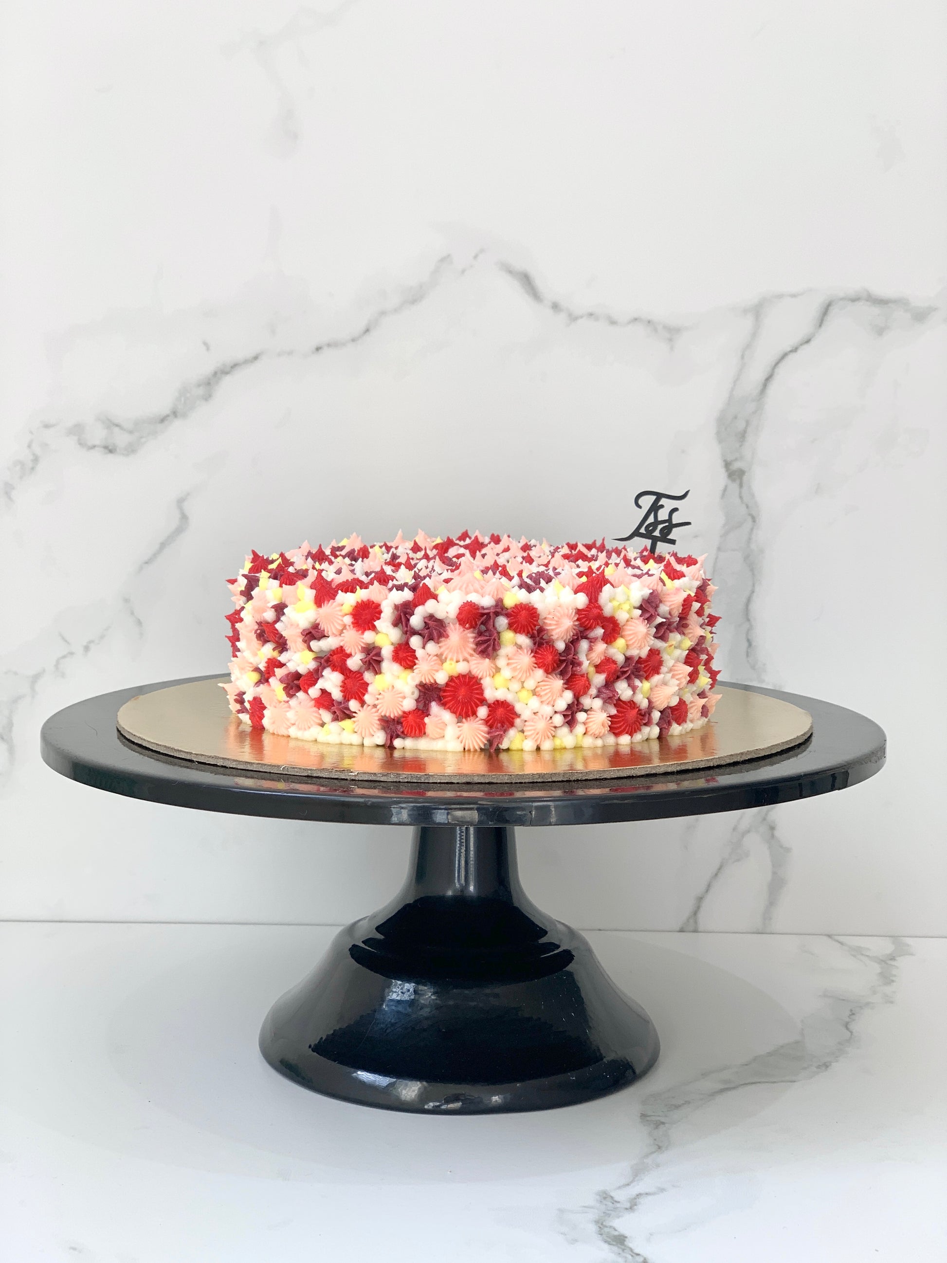 A classic cake from The Sinful Spoon with creamy frosting and decorative toppings, displayed on a platter.