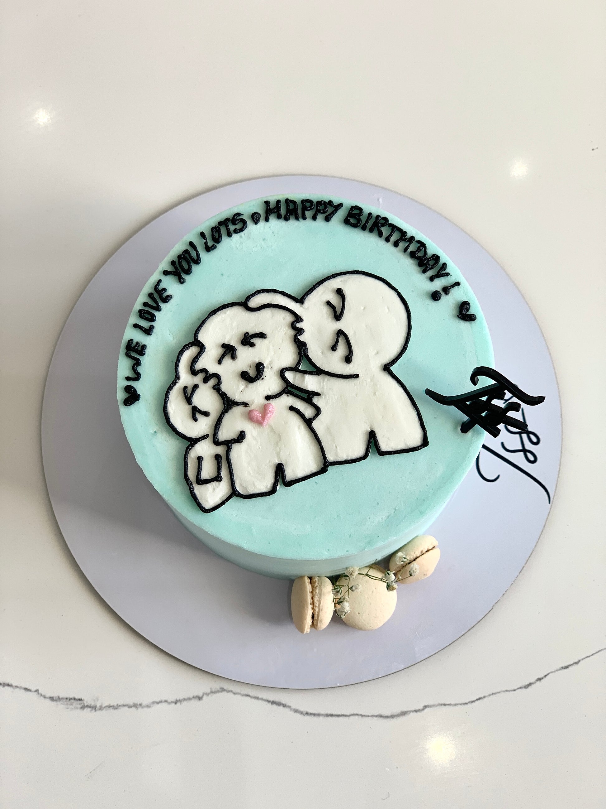 Decorative Mother's Day cake from The Sinful Spoon with floral frosting and festive design on a white cake stand.