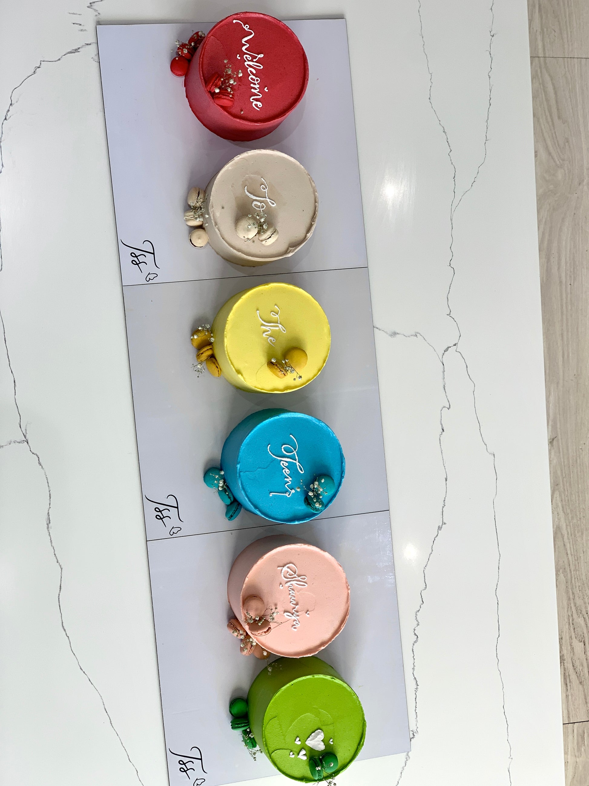 Assorted colorful Bento cakes from The Sinful Spoon with decorative toppings on a white plate.