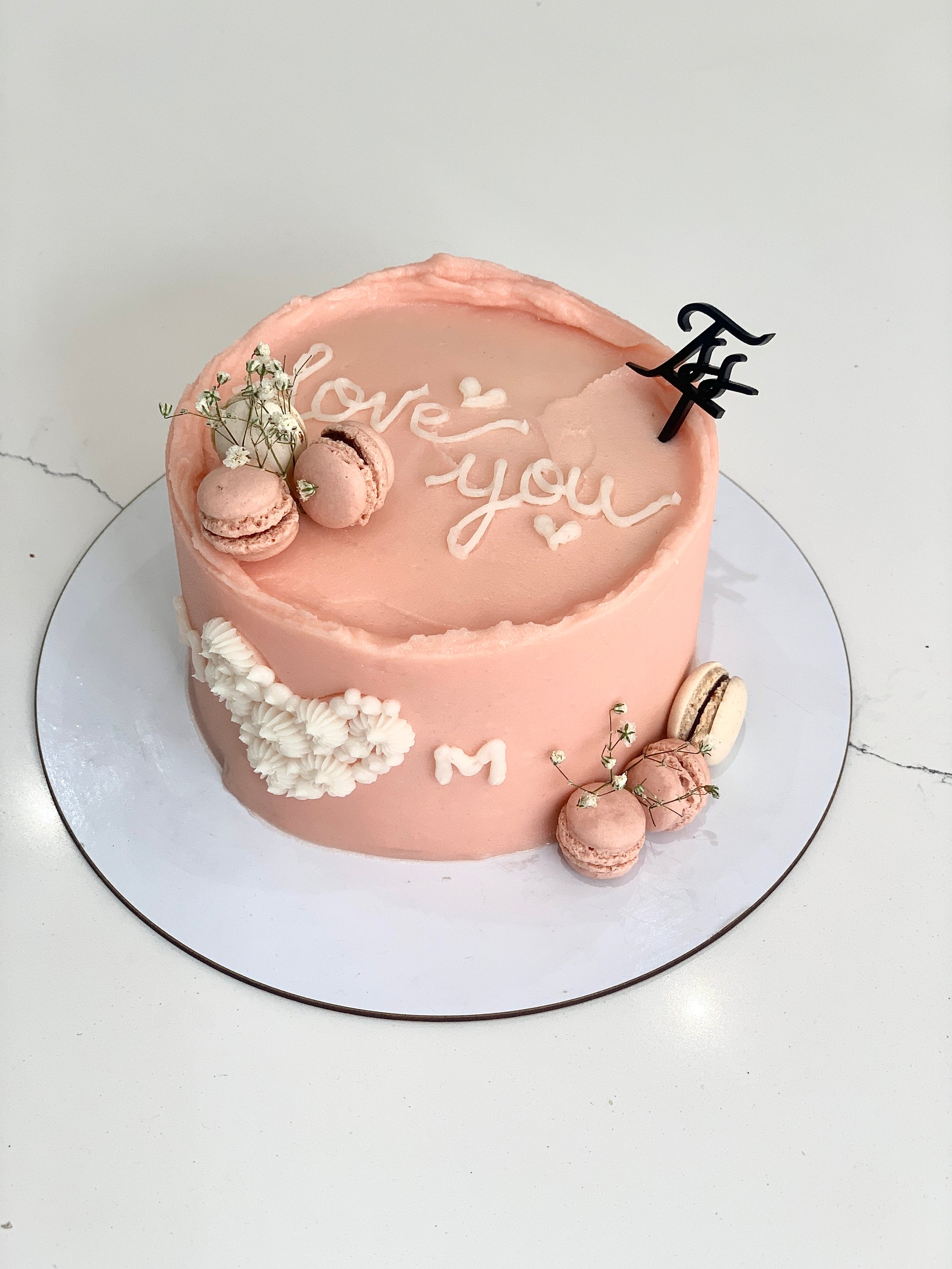 Decorative Mother's Day cake from The Sinful Spoon with floral icing and colorful toppings, perfect for celebrating moms.