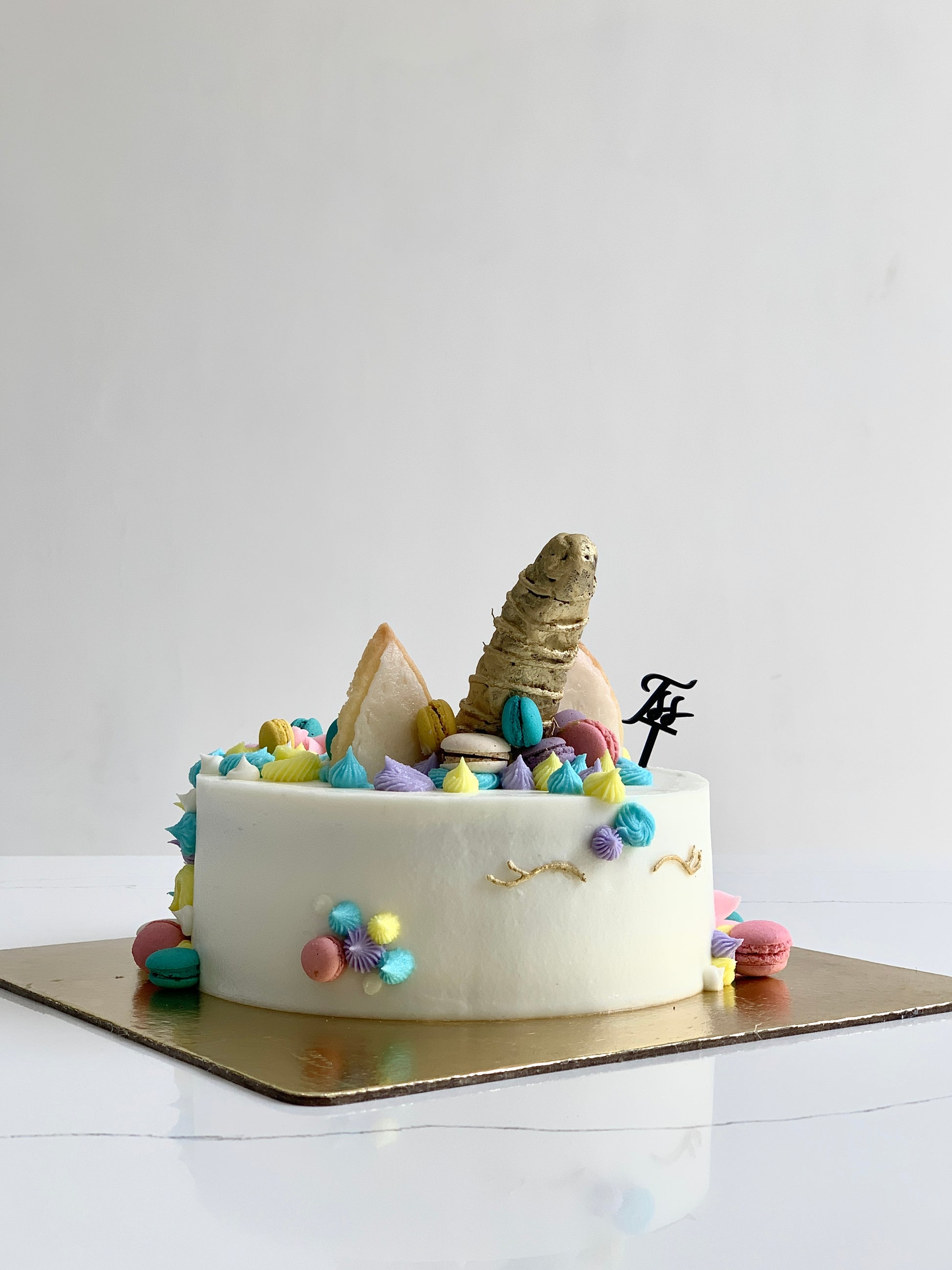 Colorful shaped cakes from The Sinful Spoon, decorated with vibrant icing and creative designs on a white plate.