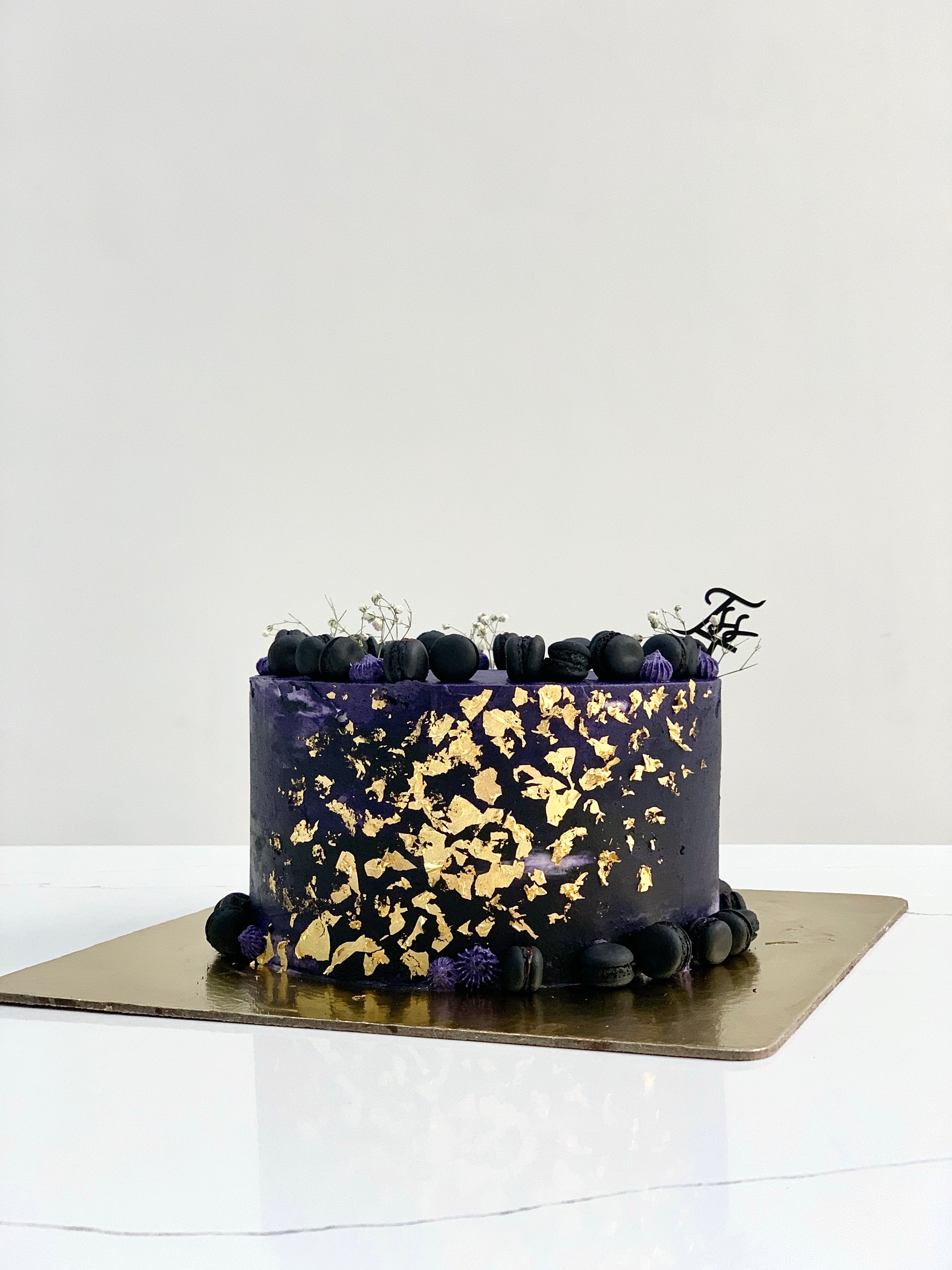 A classic cake from The Sinful Spoon with creamy frosting and decorative toppings on a white plate.