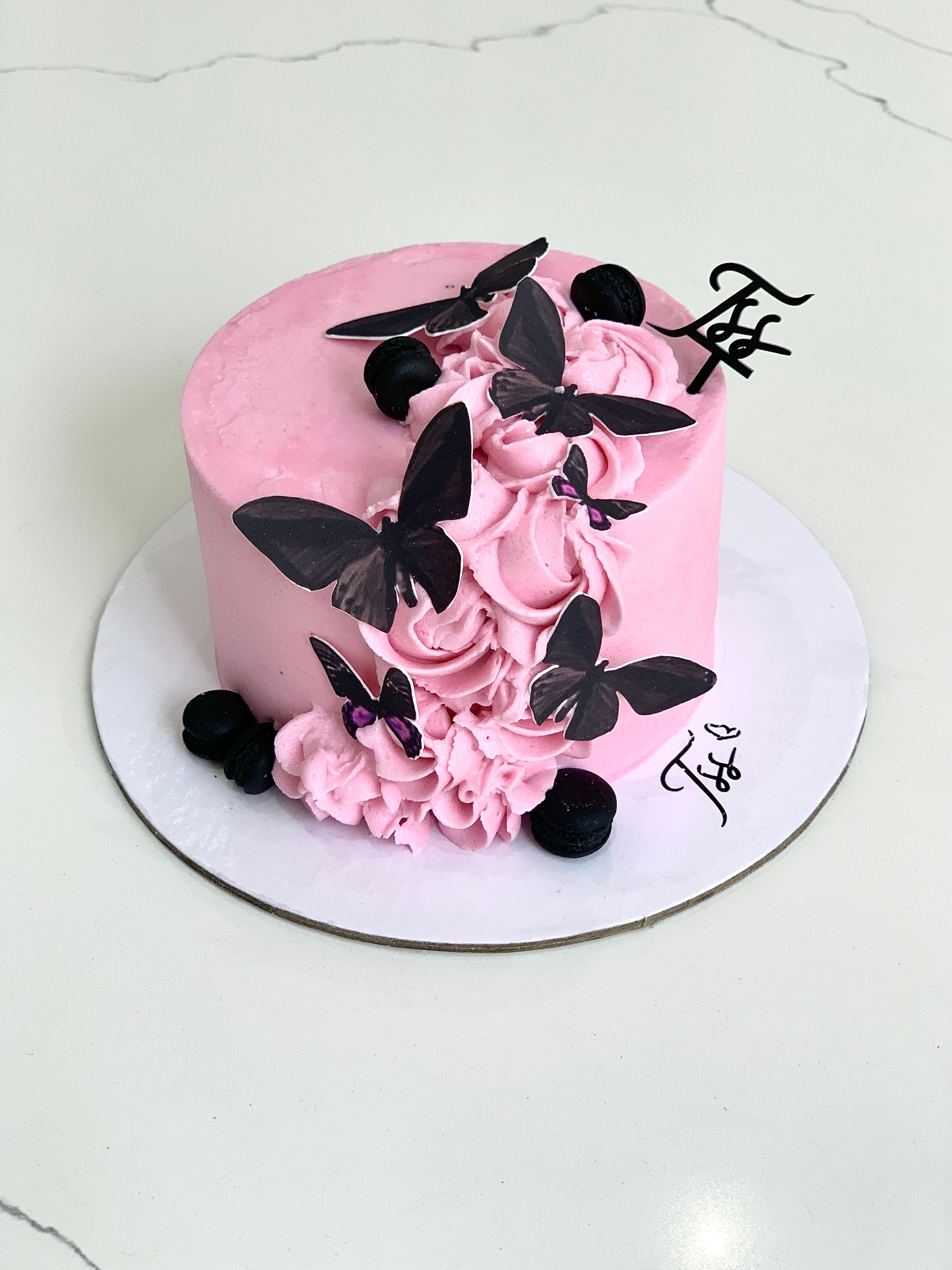 Edible paper cake for baby girl by The Sinful Spoon, decorated with pink and white icing and baby-themed edible decorations.