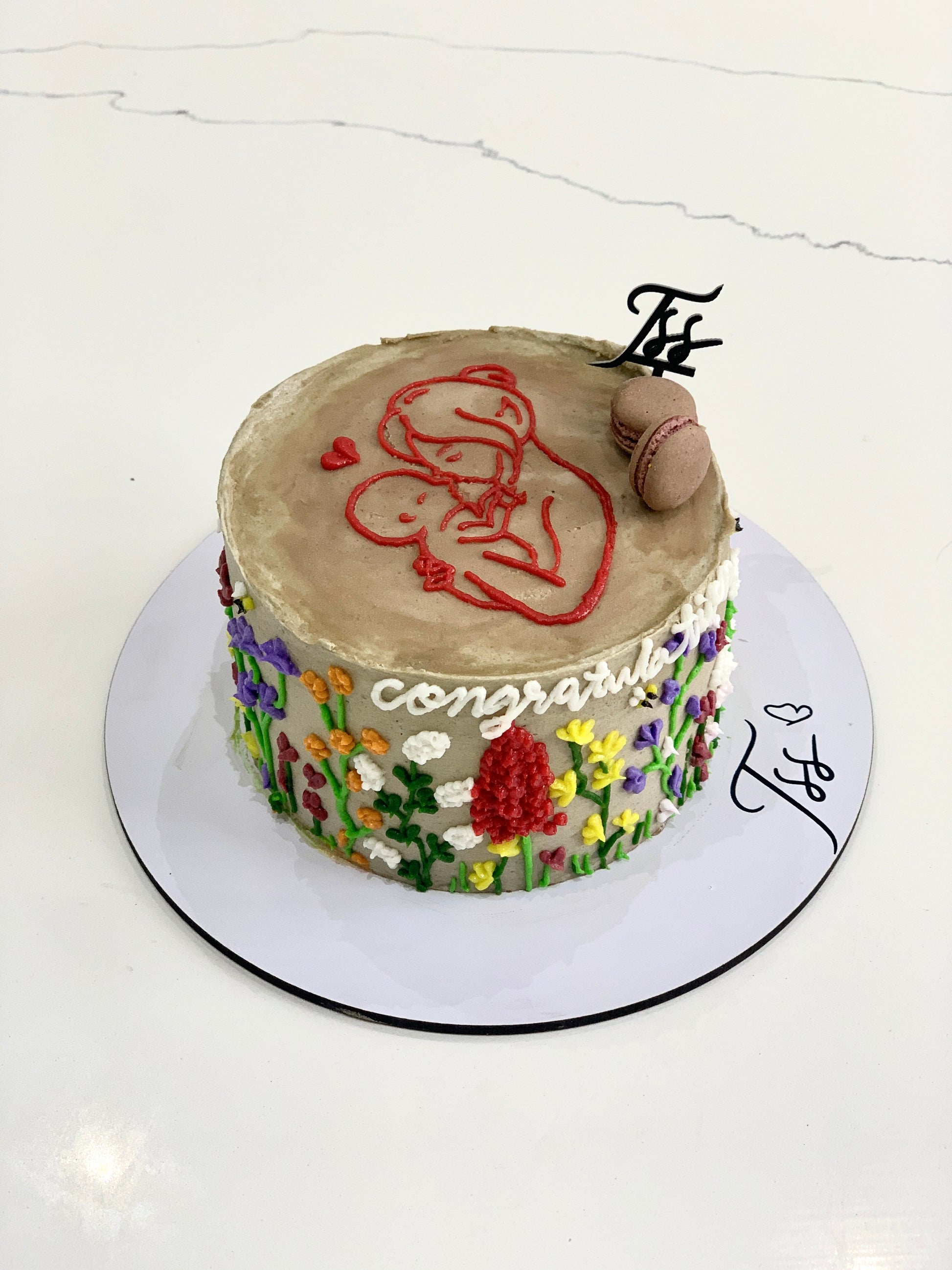 Decorative Mother's Day cake from The Sinful Spoon, featuring floral designs and colorful icing on a festive celebration cake.