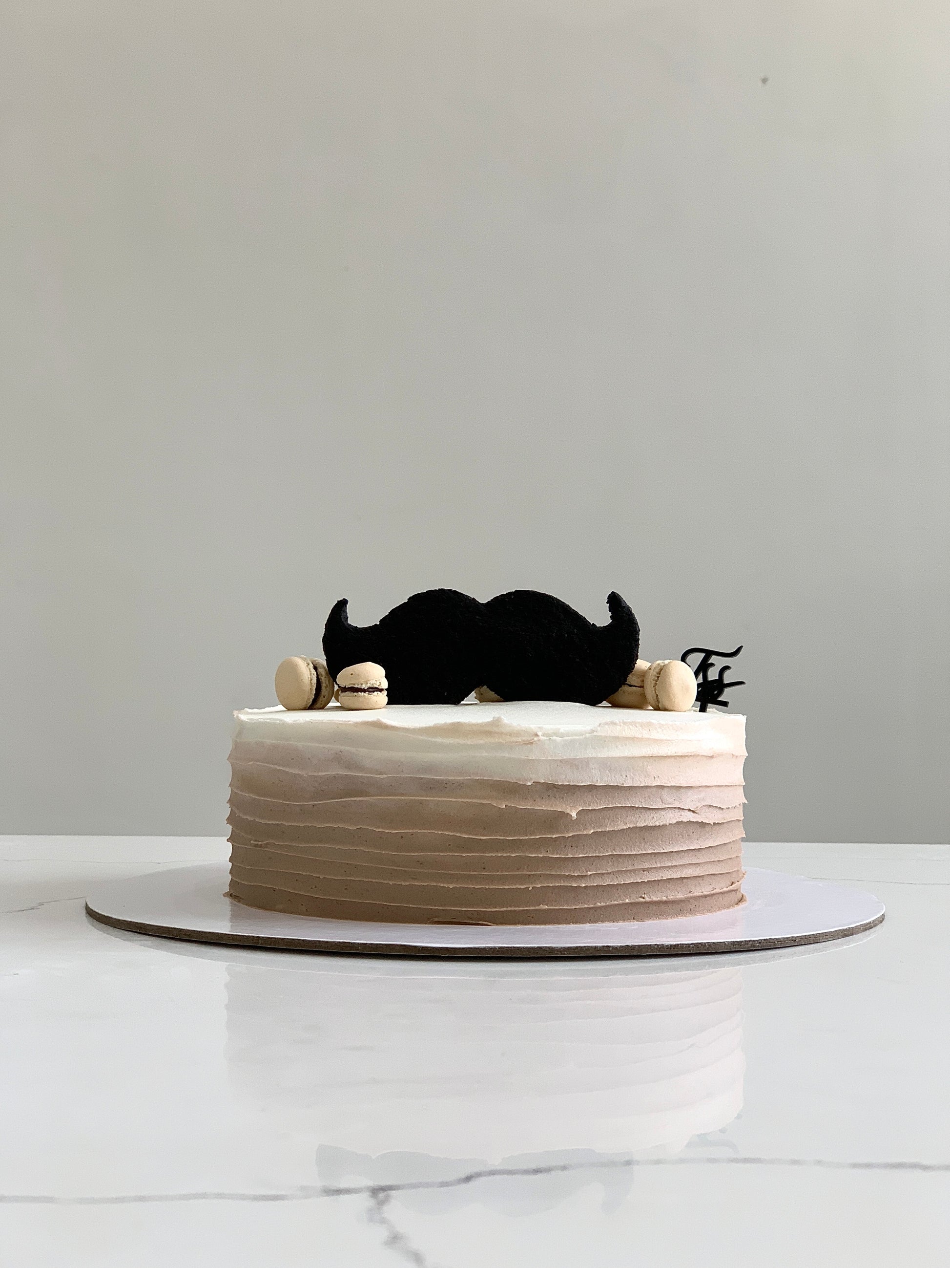 Decorative Father's Day cake from The Sinful Spoon with chocolate frosting and themed toppings on a white plate.