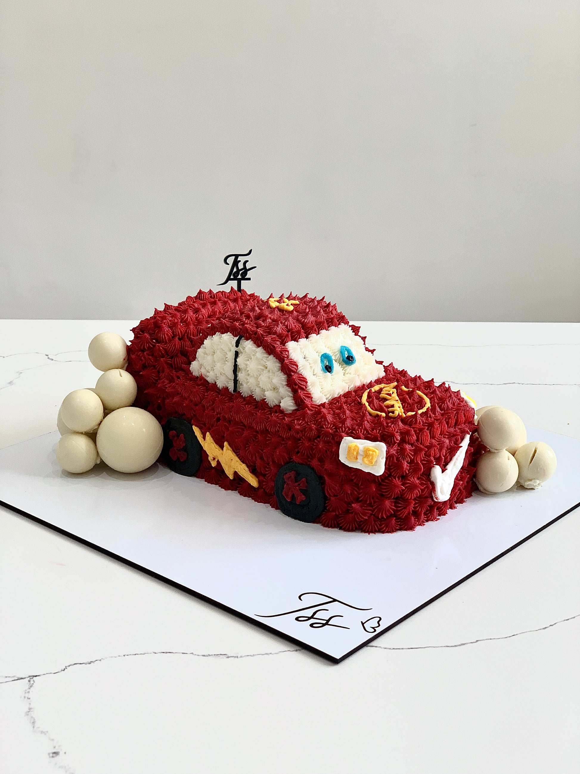Decorative shape cakes from The Sinful Spoon featuring colorful icing and creative designs on a white platter.