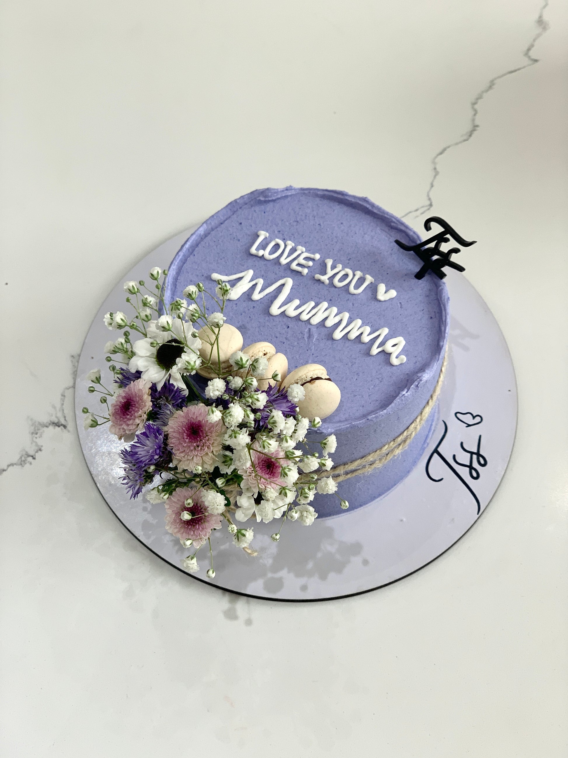 Fresh floral cakes by The Sinful Spoon with colorful icing and decorative edible flowers on a white cake.