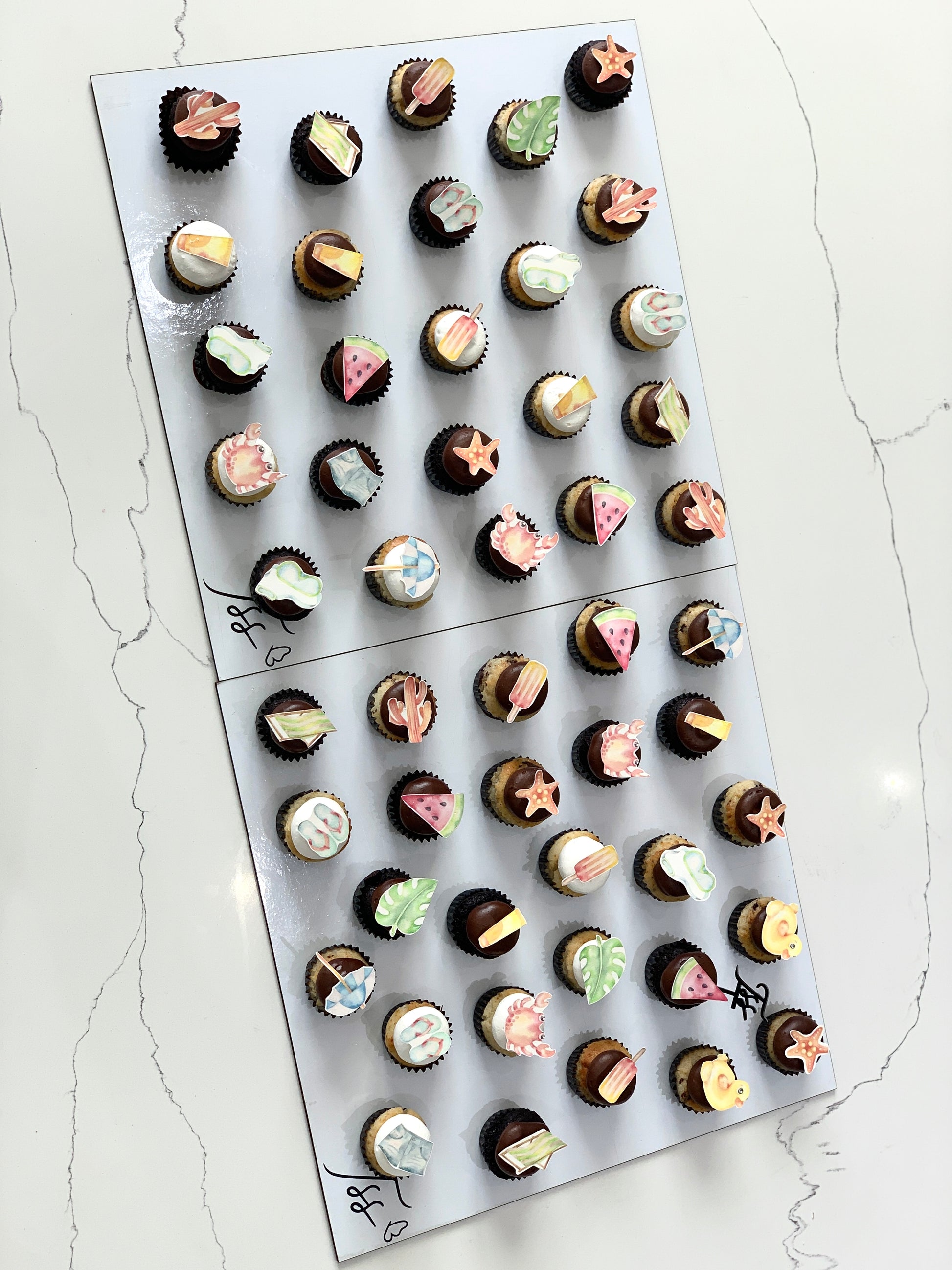 Colorful cupcakes with swirled frosting and sprinkles from The Sinful Spoon, displayed on a white plate.