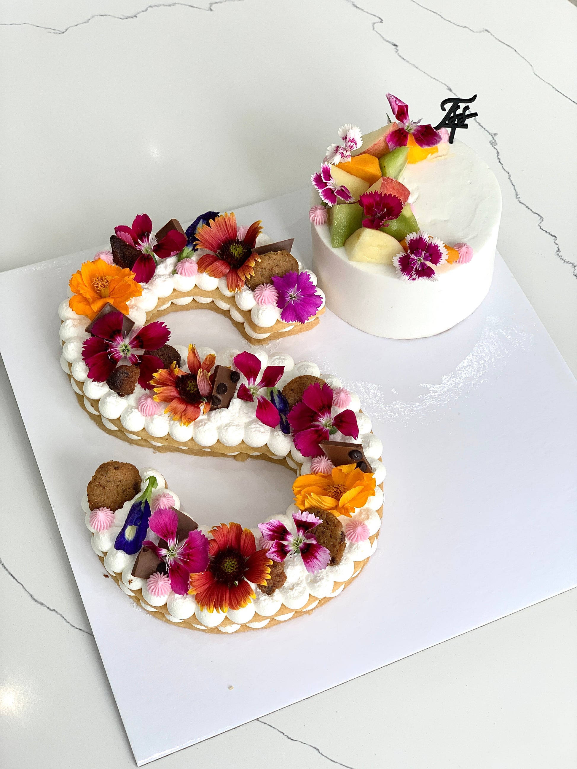 Fresh fruit cakes from The Sinful Spoon featuring vibrant layered cakes topped with colorful fruit and icing.