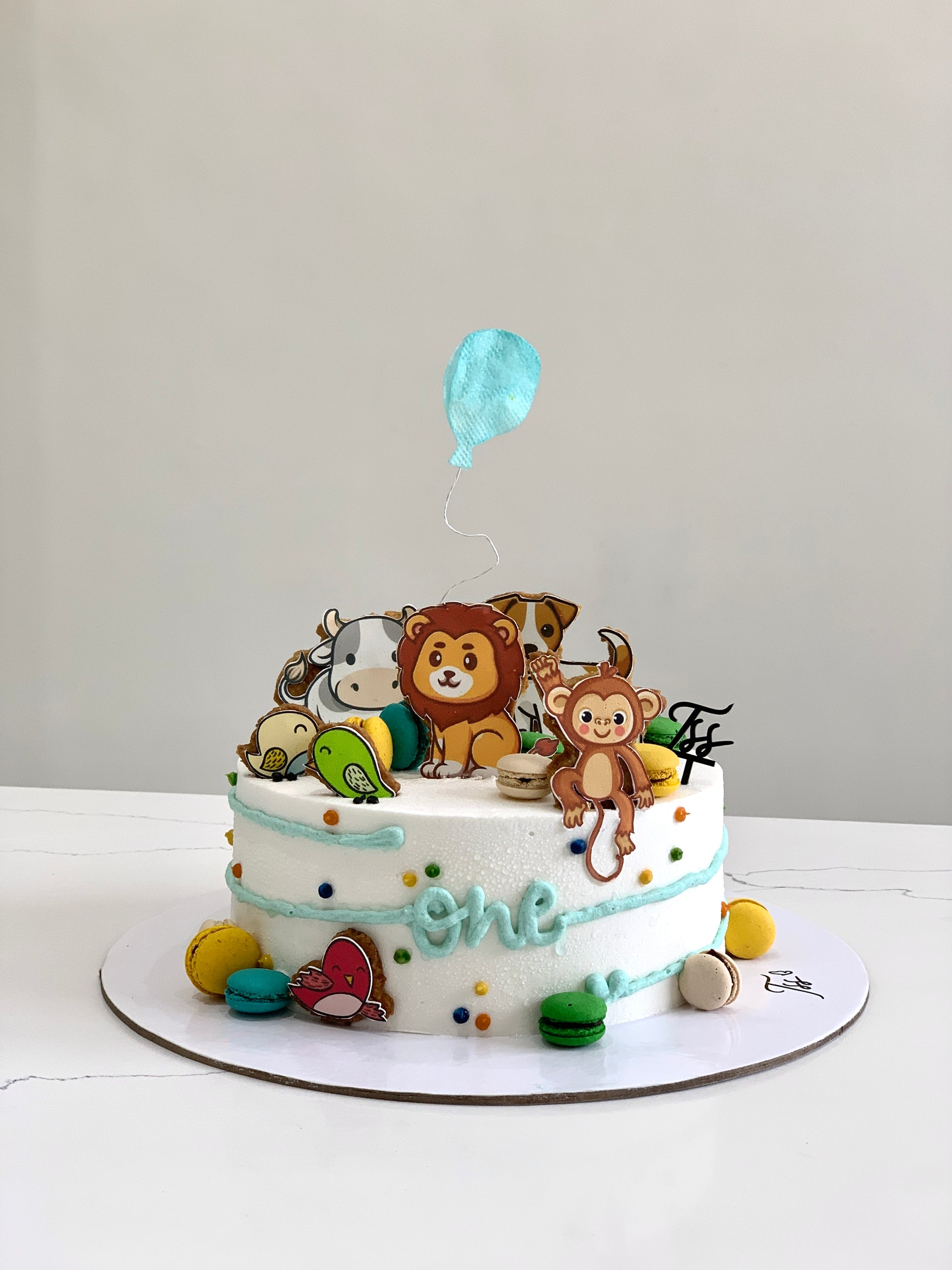 Edible paper cake decorated for a baby boy celebration by The Sinful Spoon, featuring blue and white design elements.