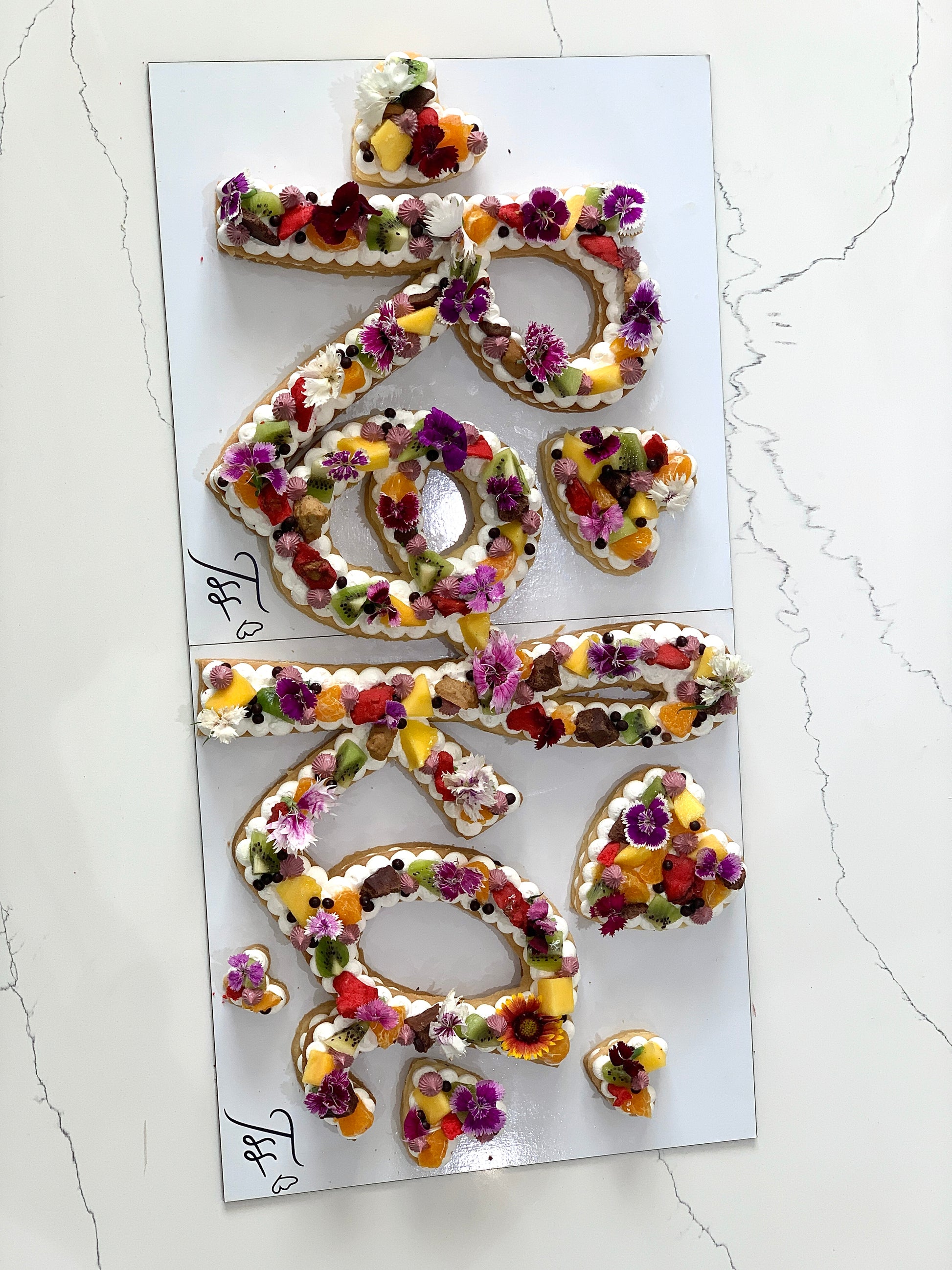 Chocolate chip cookie cake from The Sinful Spoon, topped with colorful sprinkles and decorated with festive icing.