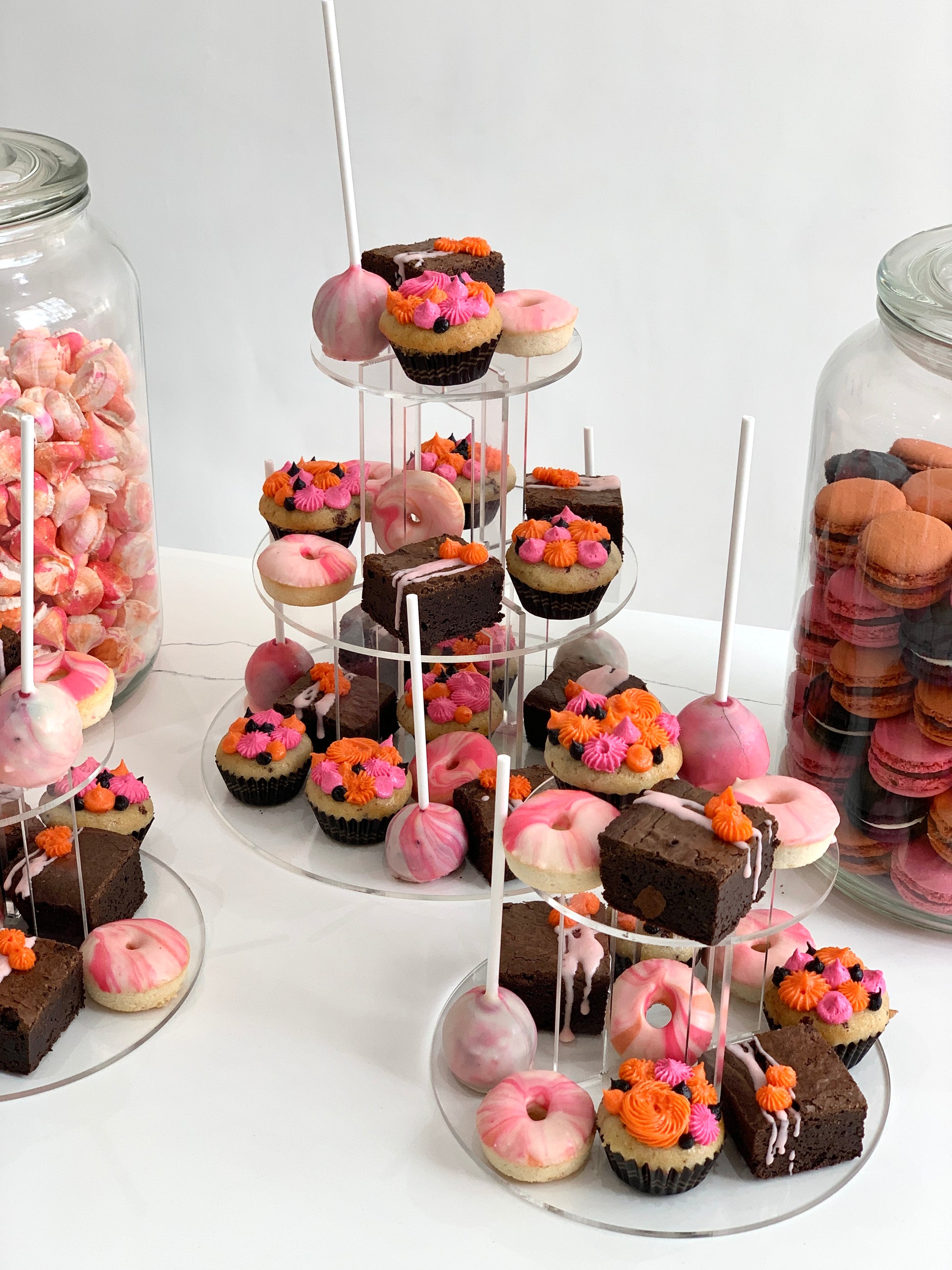 Colorful cupcakes with swirled frosting and sprinkles from The Sinful Spoon on a white plate.