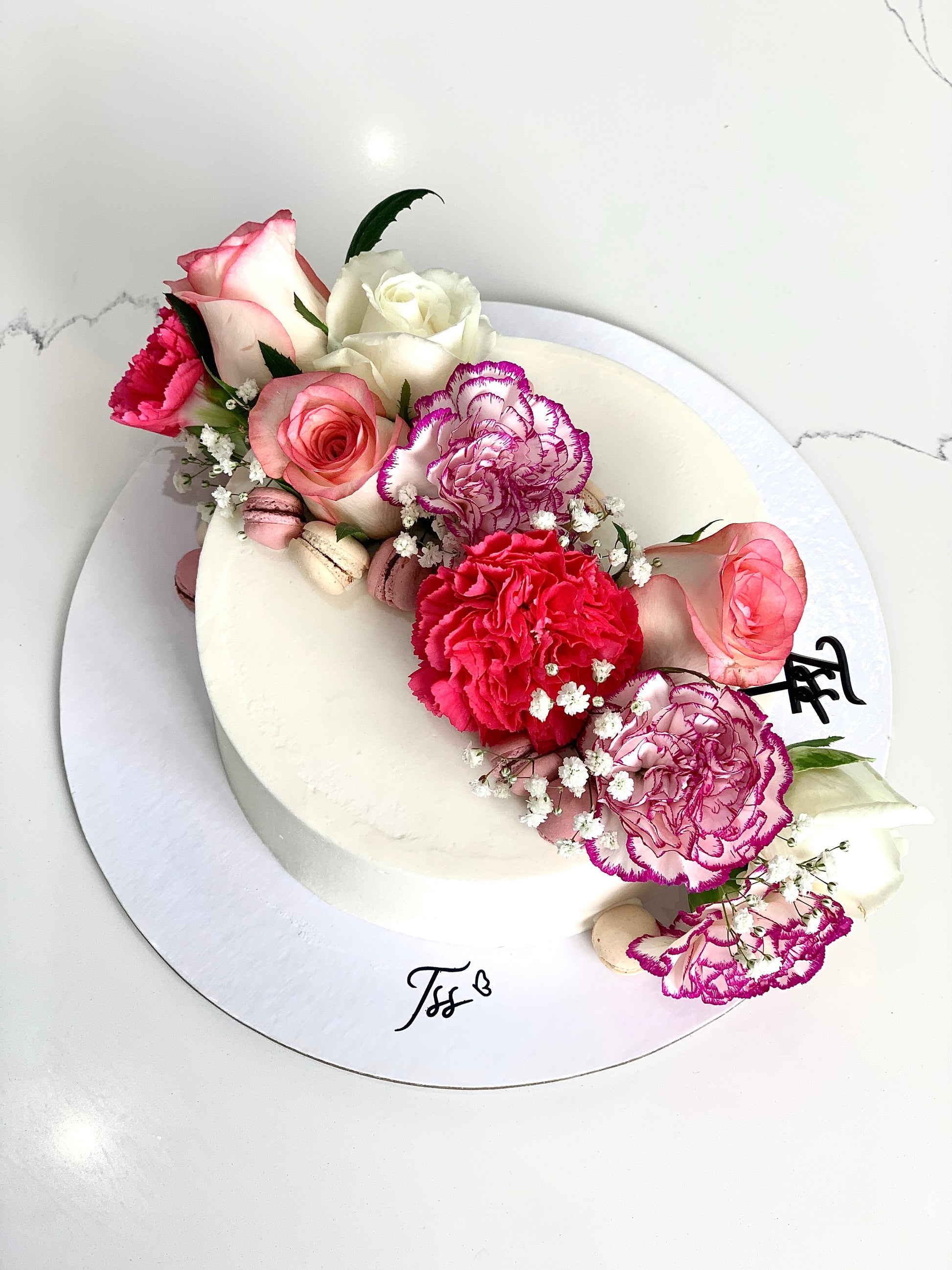 Fresh floral cake from The Sinful Spoon featuring colorful edible flowers and intricate frosting decoration.