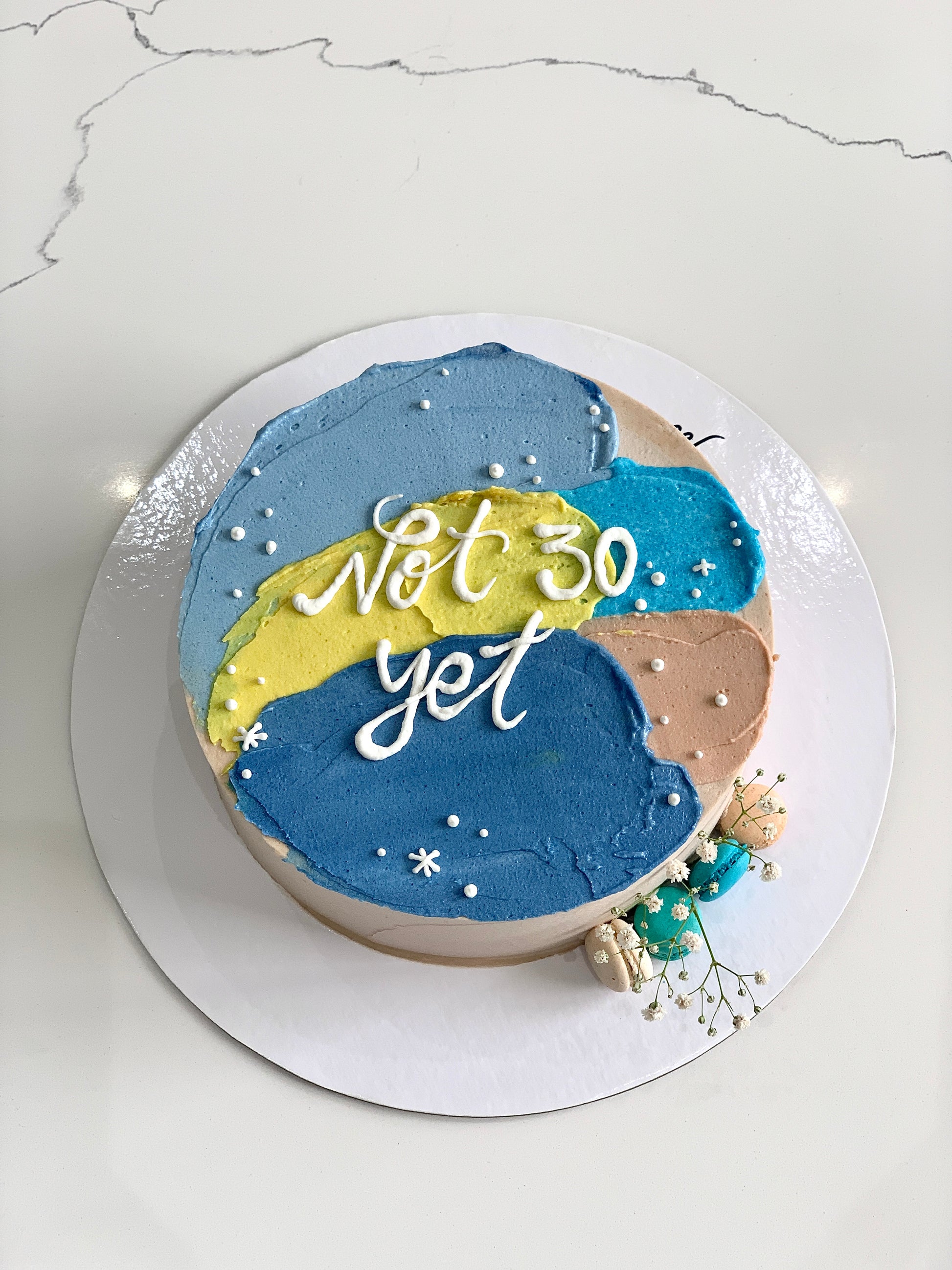 Colorful bento cakes from The Sinful Spoon with layered frosting and decorative toppings, displayed on a white plate.
