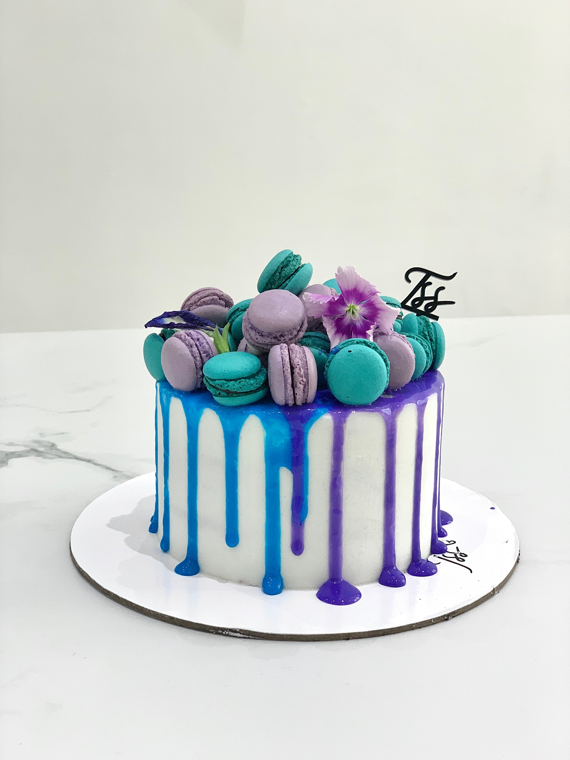 Slice of classic cake from The Sinful Spoon showcasing layered sponge, creamy frosting, and decorative toppings on a plate.