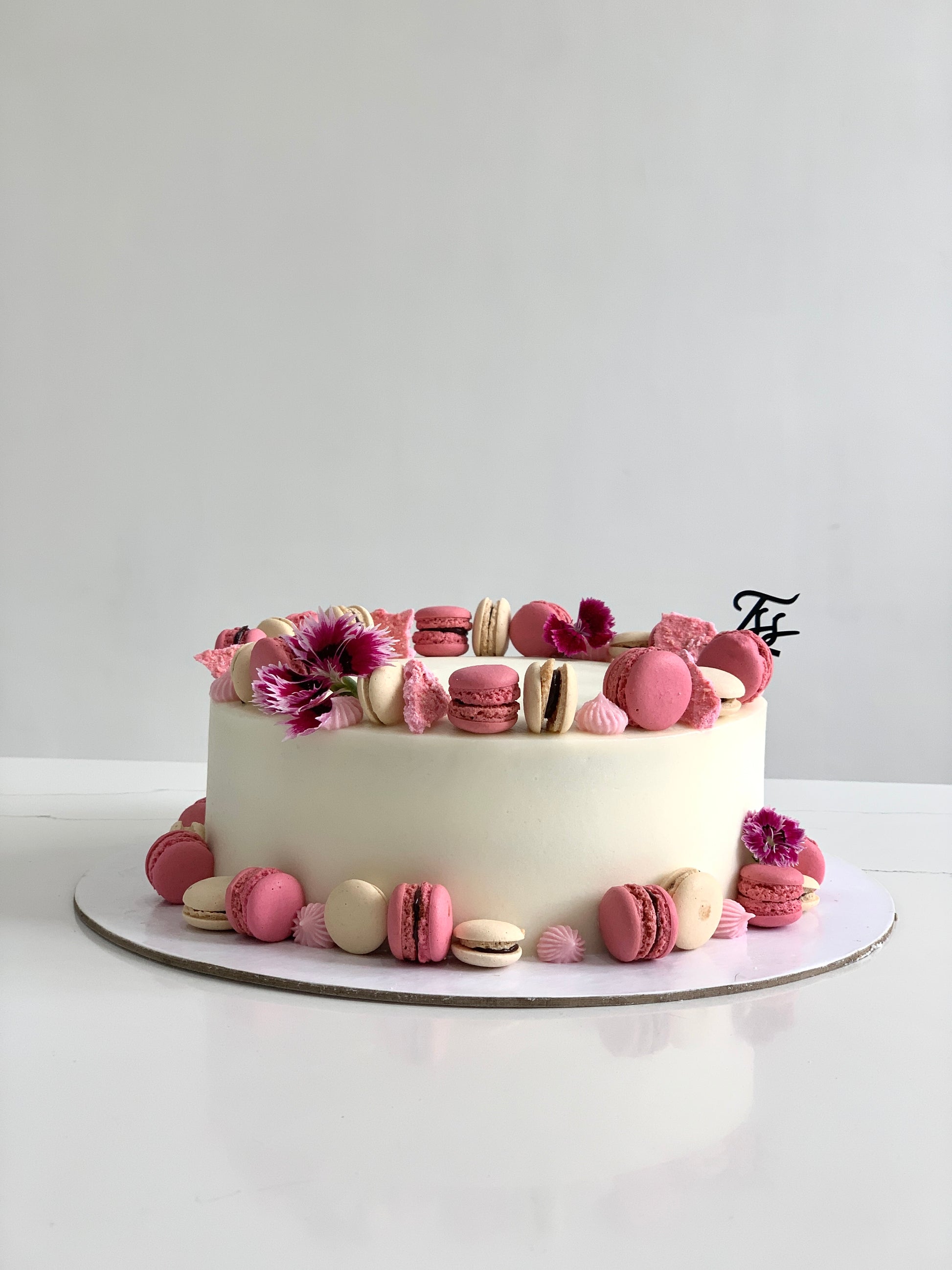 A classic cake from The Sinful Spoon with creamy frosting and decorative toppings, displayed on a plate.